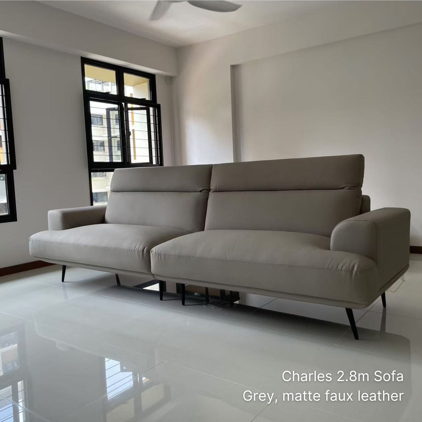 Gray 4 seater Charles faux leather sofa in a modern living room with white walls and tiled floor.