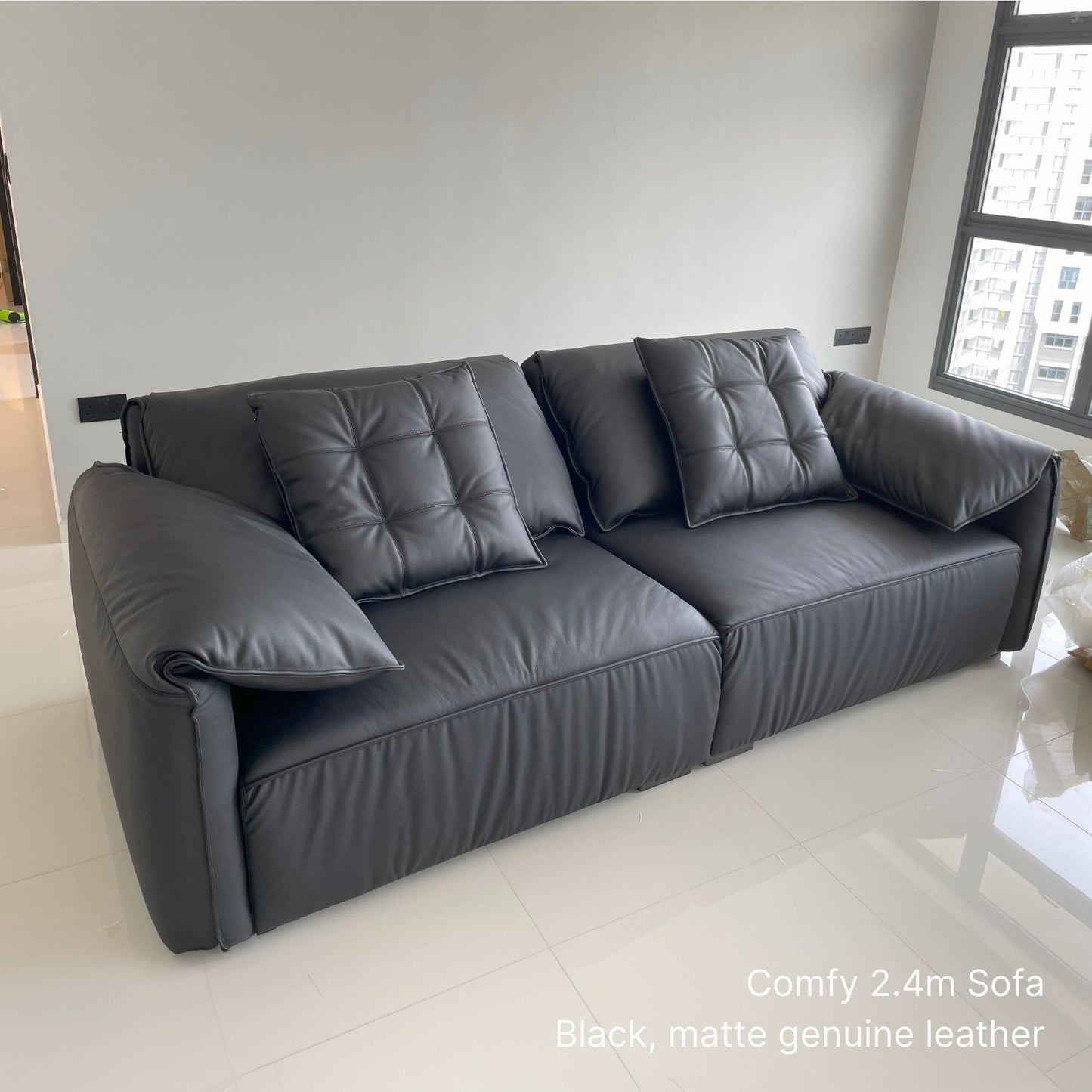 3 seater 220cm black Comfy half leather sofa in a modern living room with large windows.