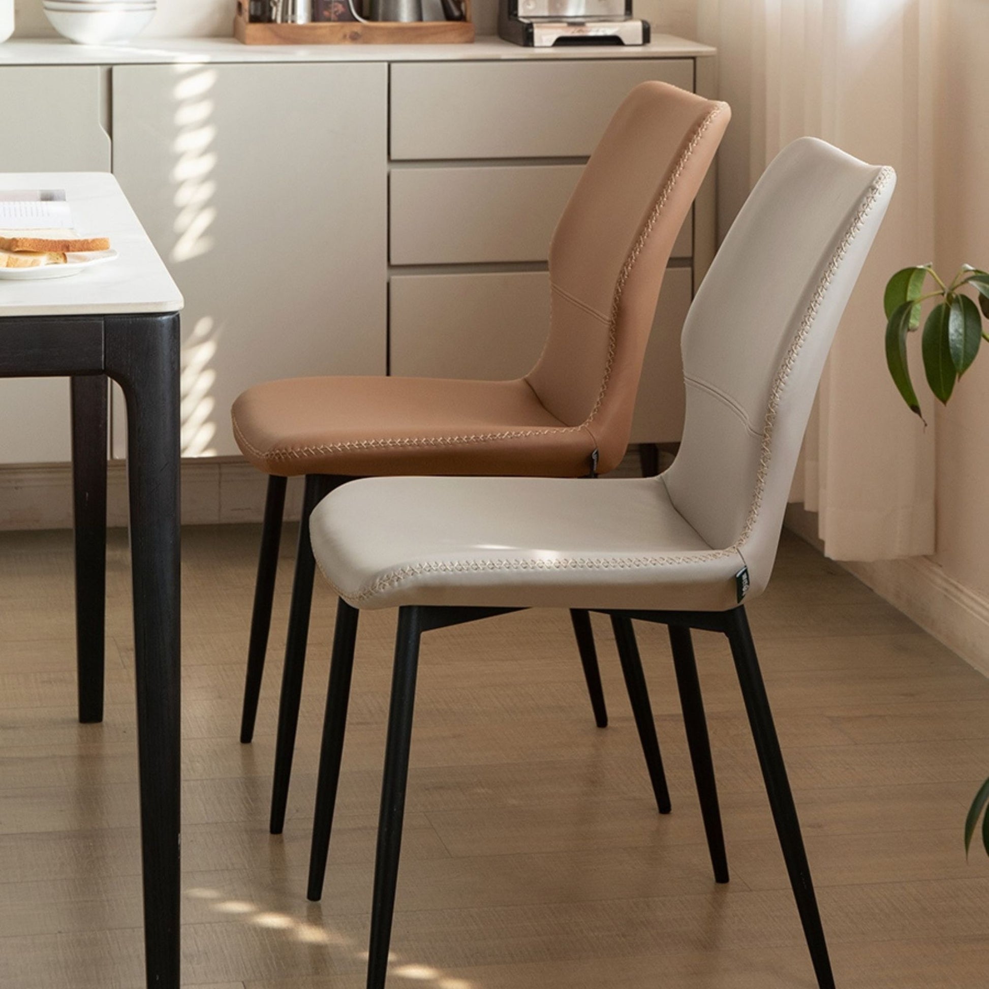 Two chairs, one brown and one grey, in a kitchen setting with a table and cabinets.