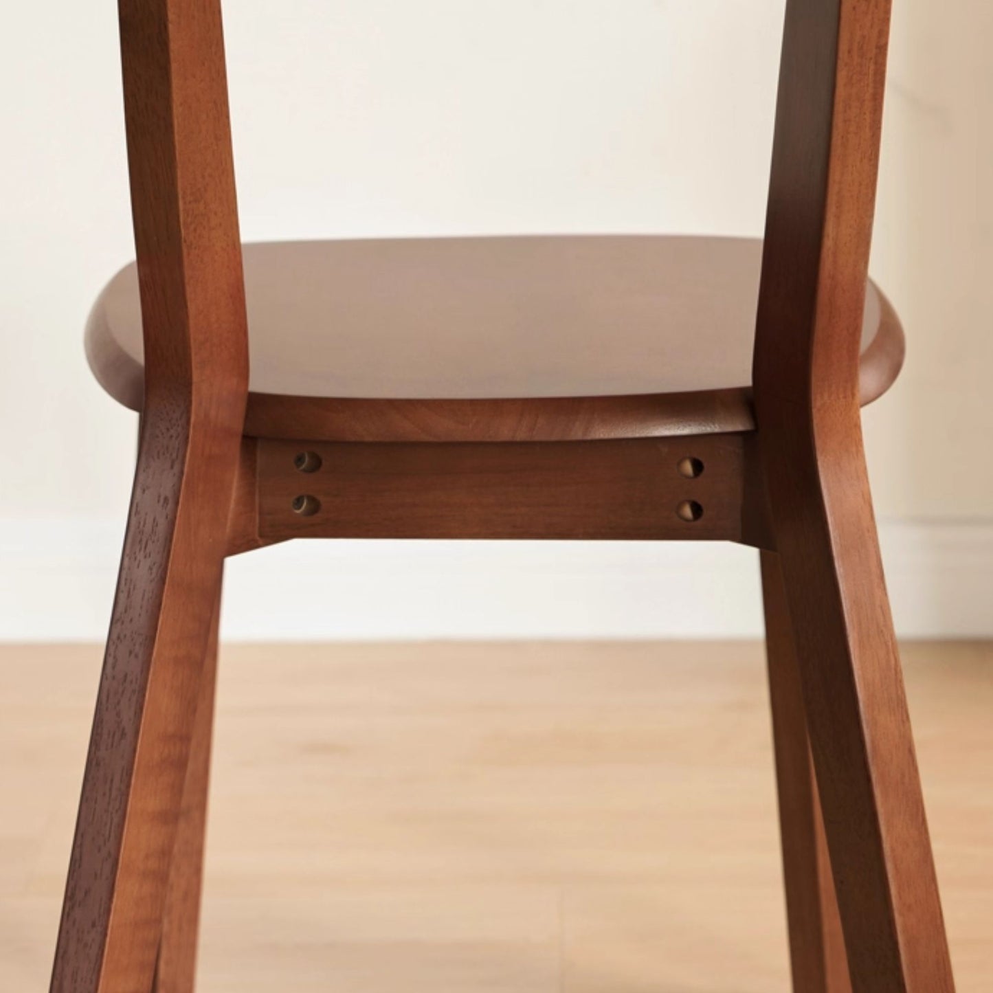 Close-up of a wooden chair with a white wall background