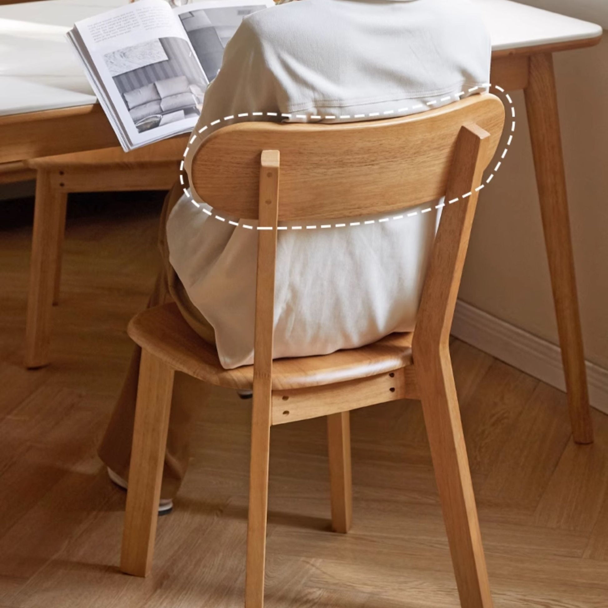 Wooden chair with a cushioned seat in a room with a desk and books.