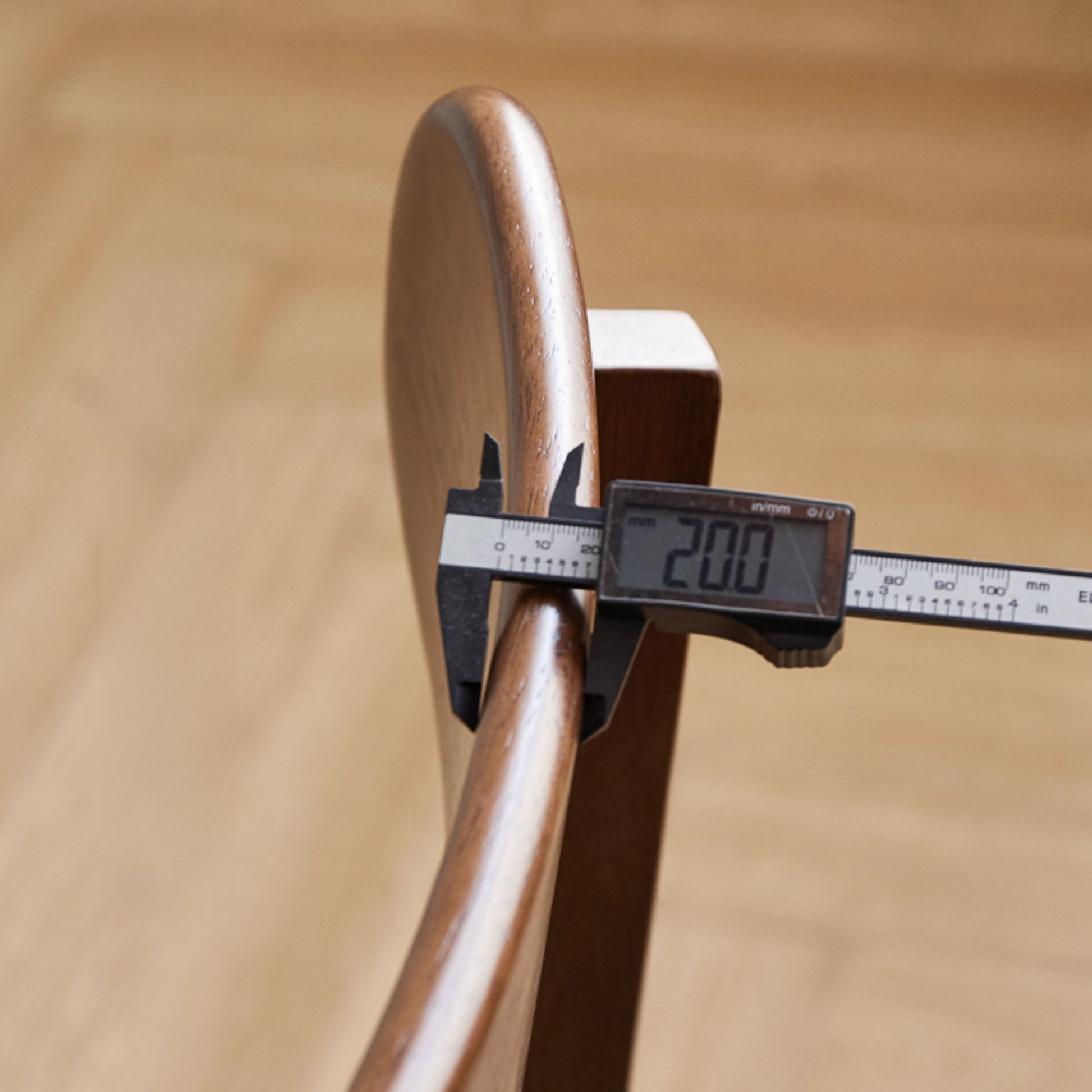 Wooden ring with digital caliper measuring its diameter on a wooden background