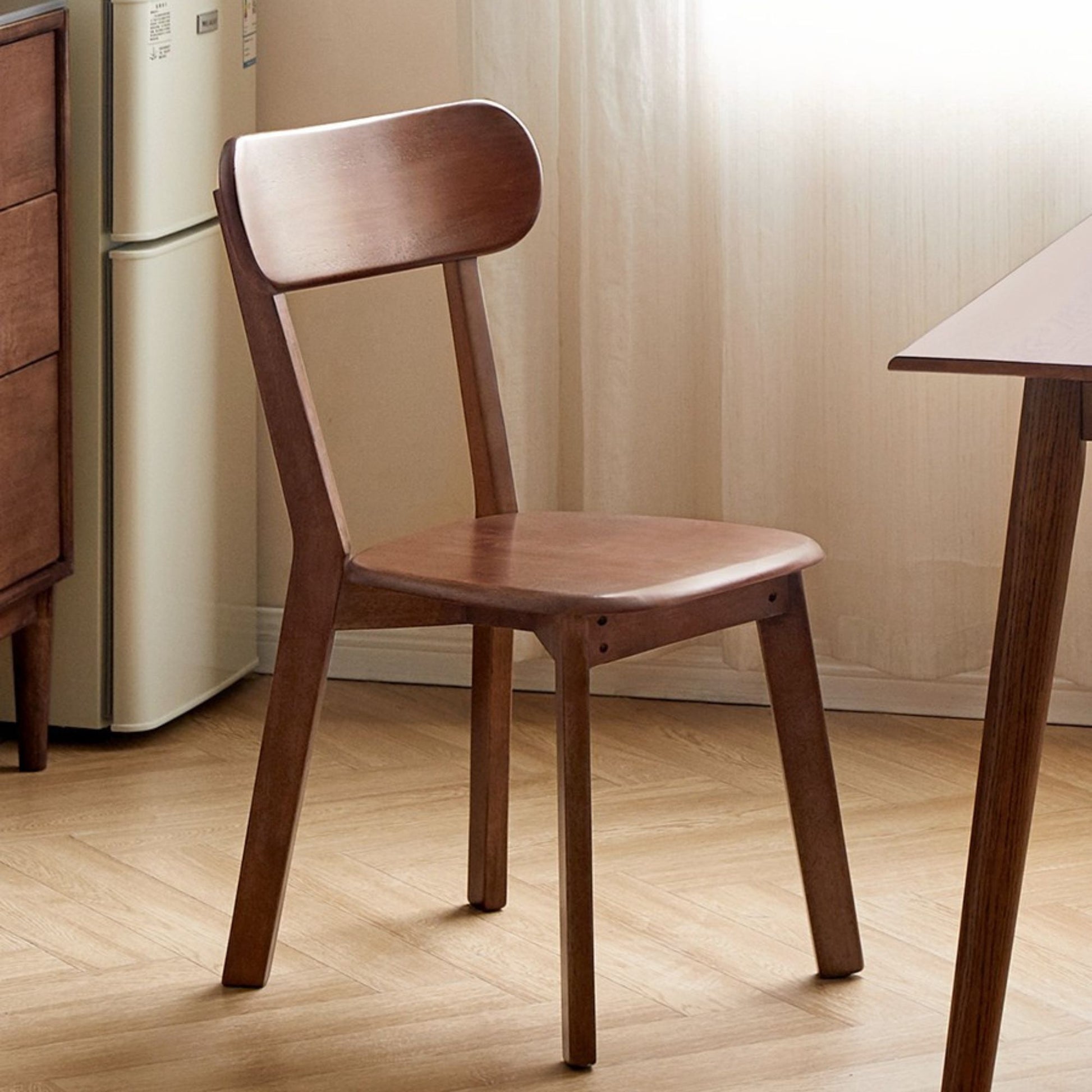 Wooden chair in a room with a refrigerator and table.