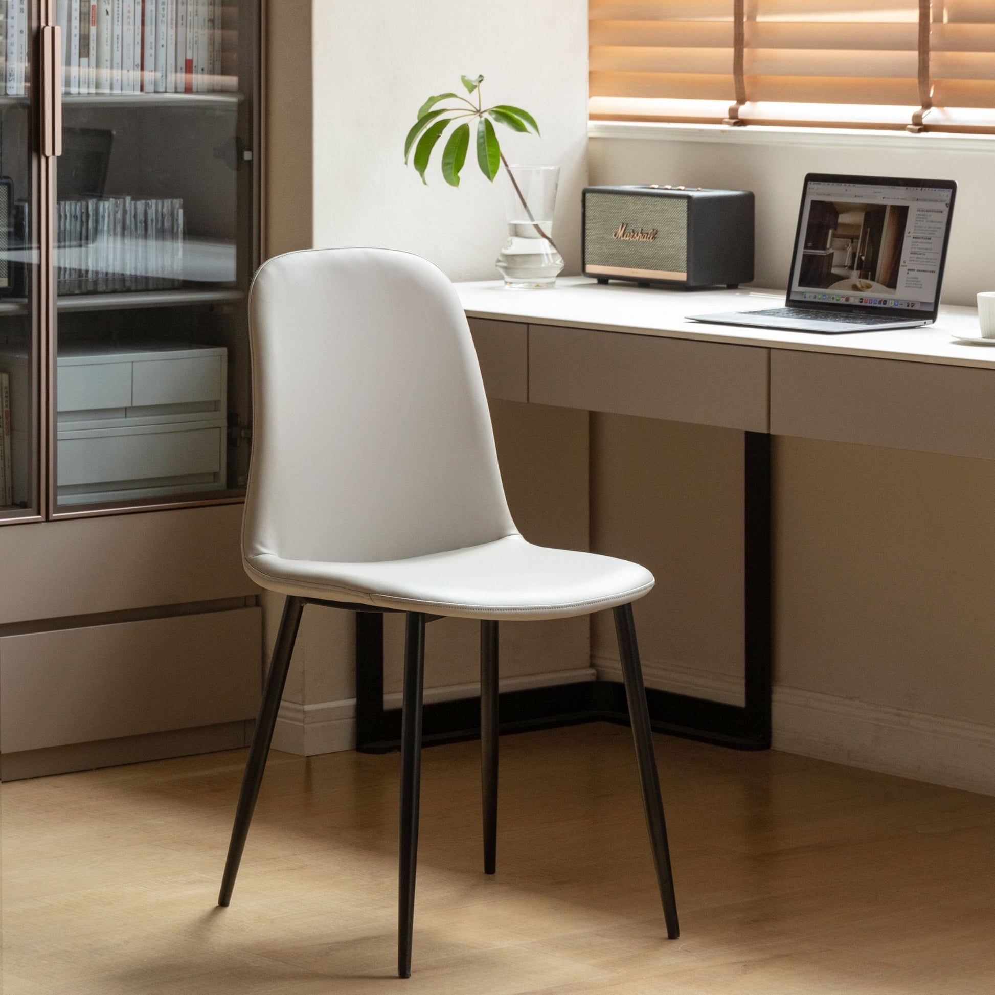 Grey chair in front of a desk with a laptop and plant in a home office setting.
