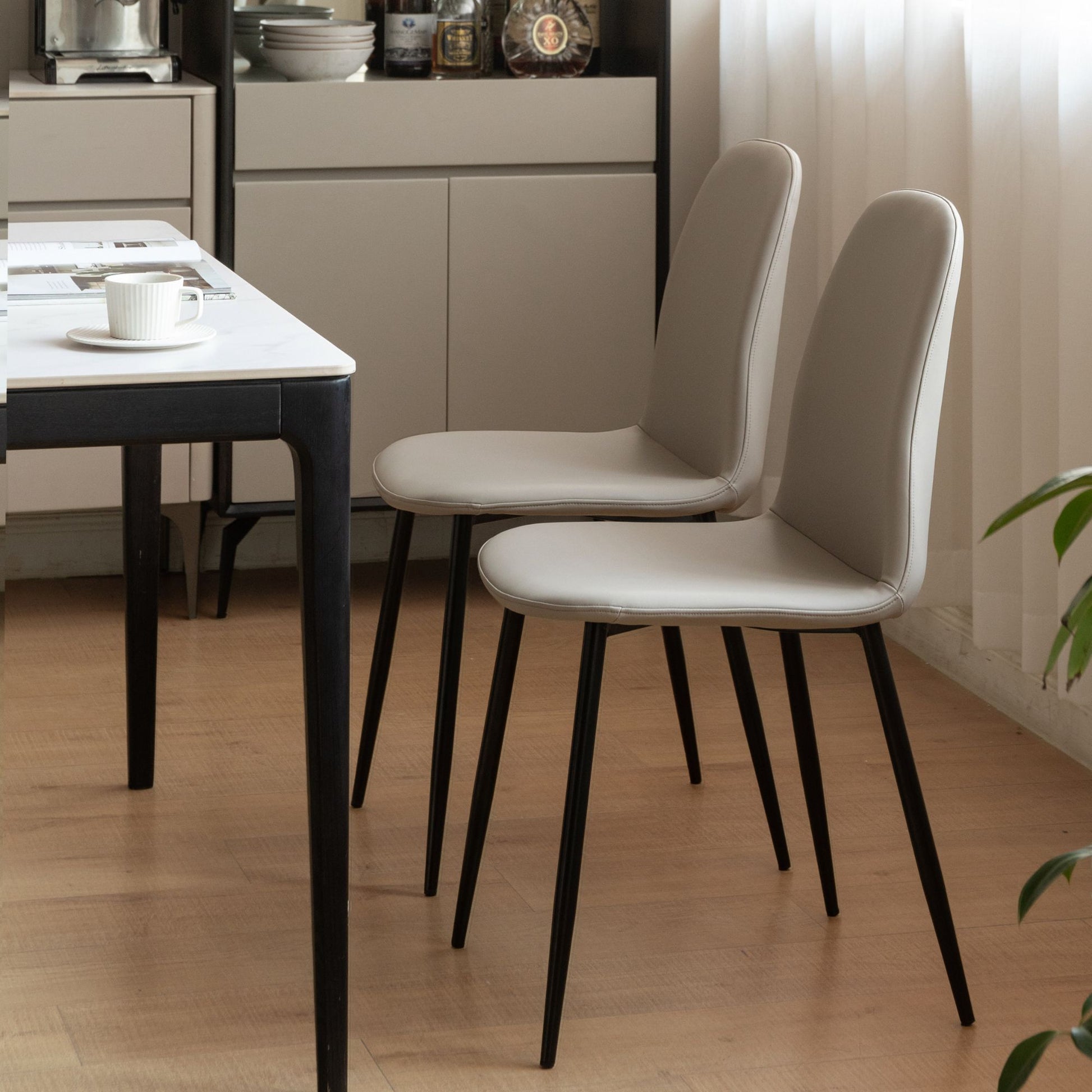 Two gray chairs with black legs in a dining room setting.