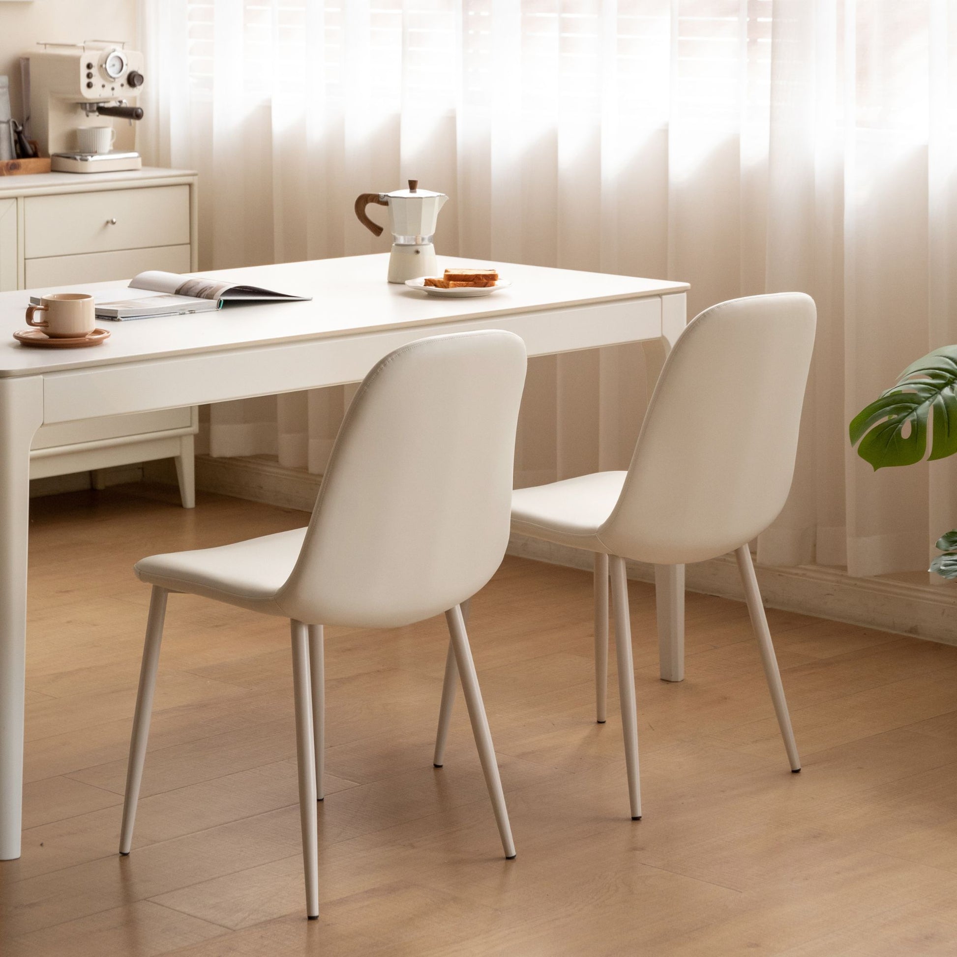 White dining table with two chairs in a bright room.