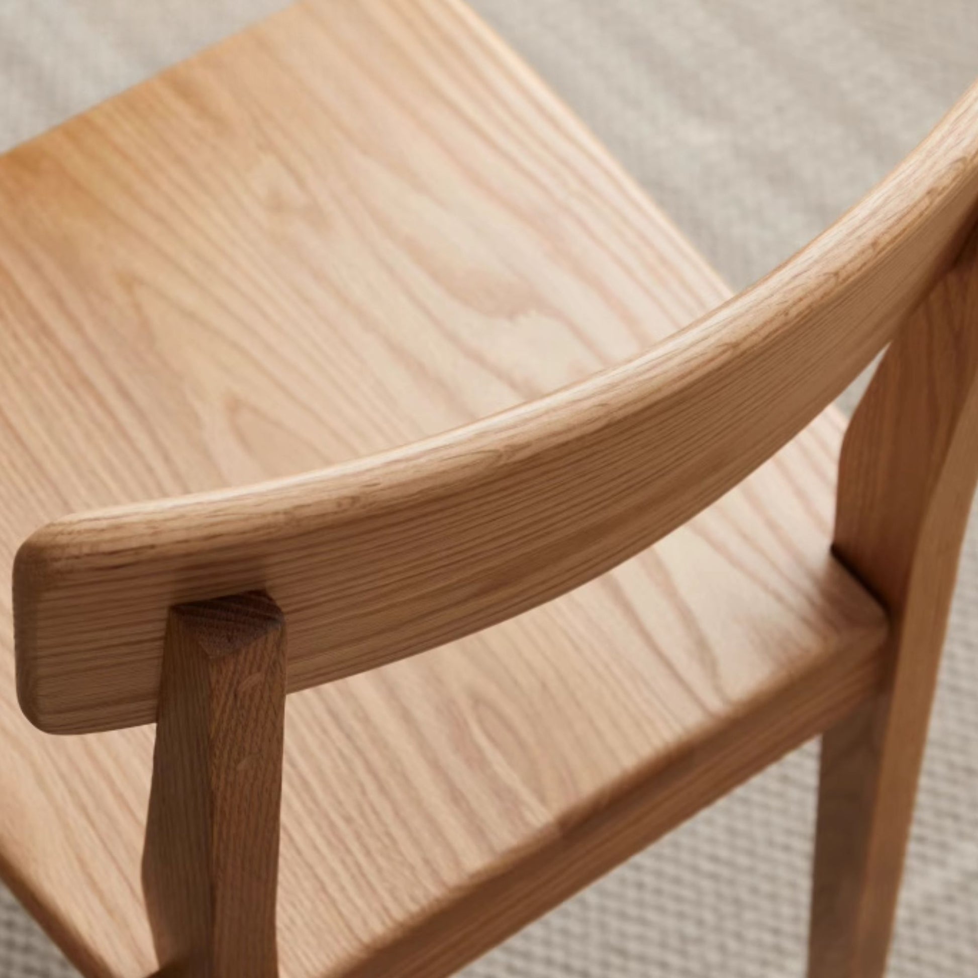 Close-up of a wooden chair with a light wood finish.