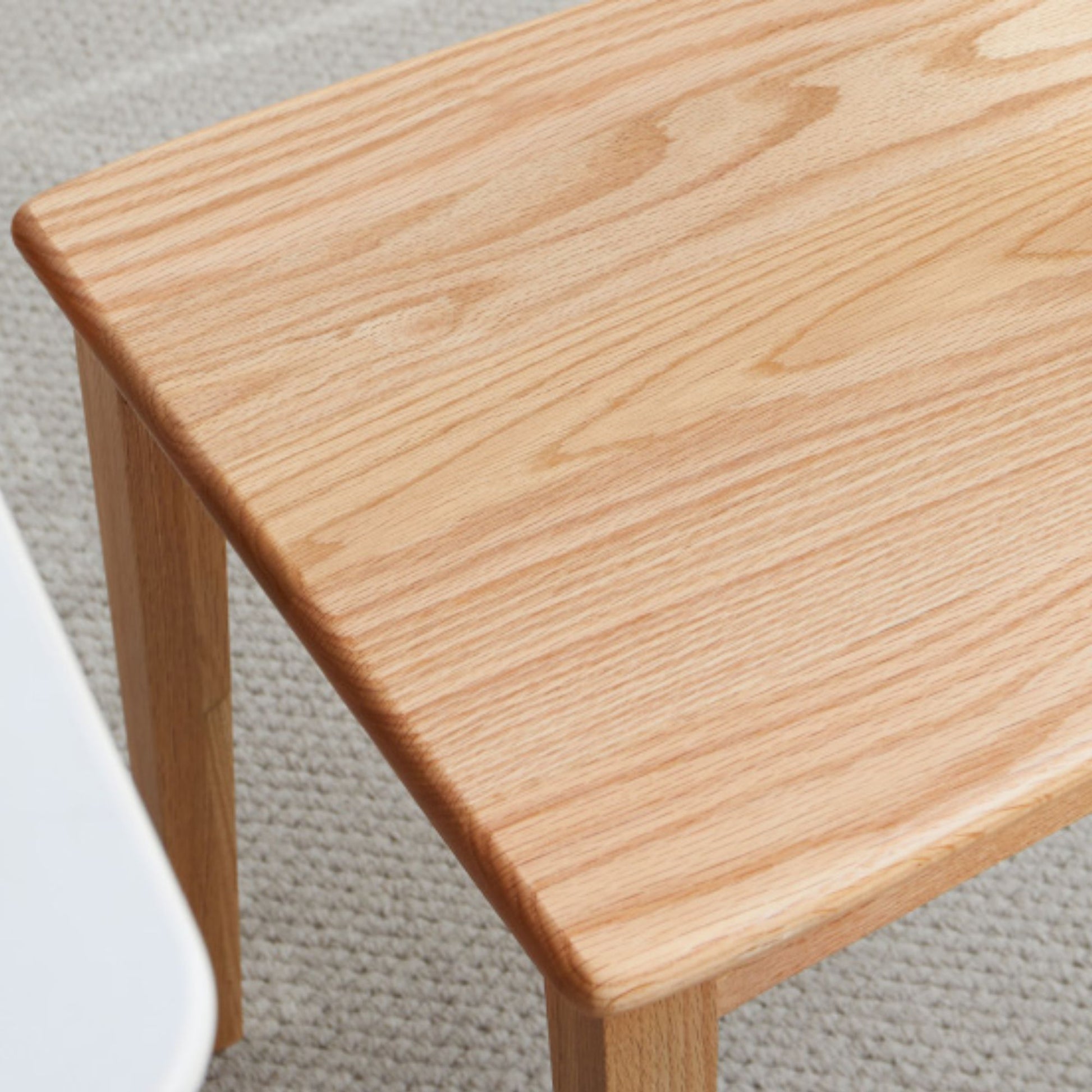 Close-up of a wooden table corner on a carpeted floor