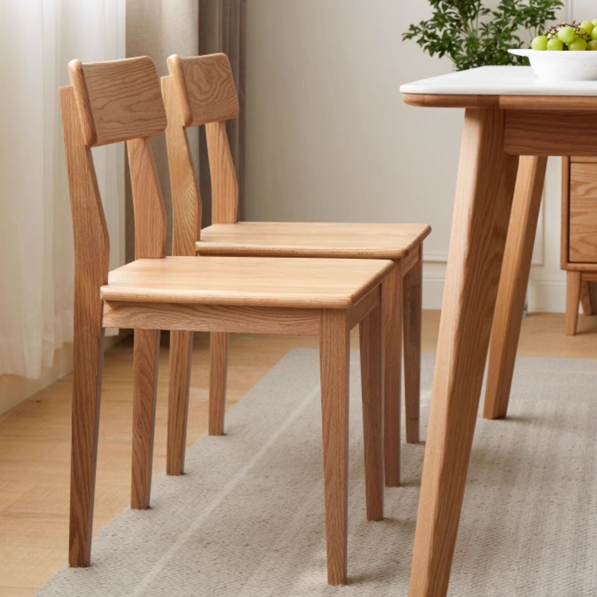 Wooden dining table and chairs in a room with a neutral color scheme.