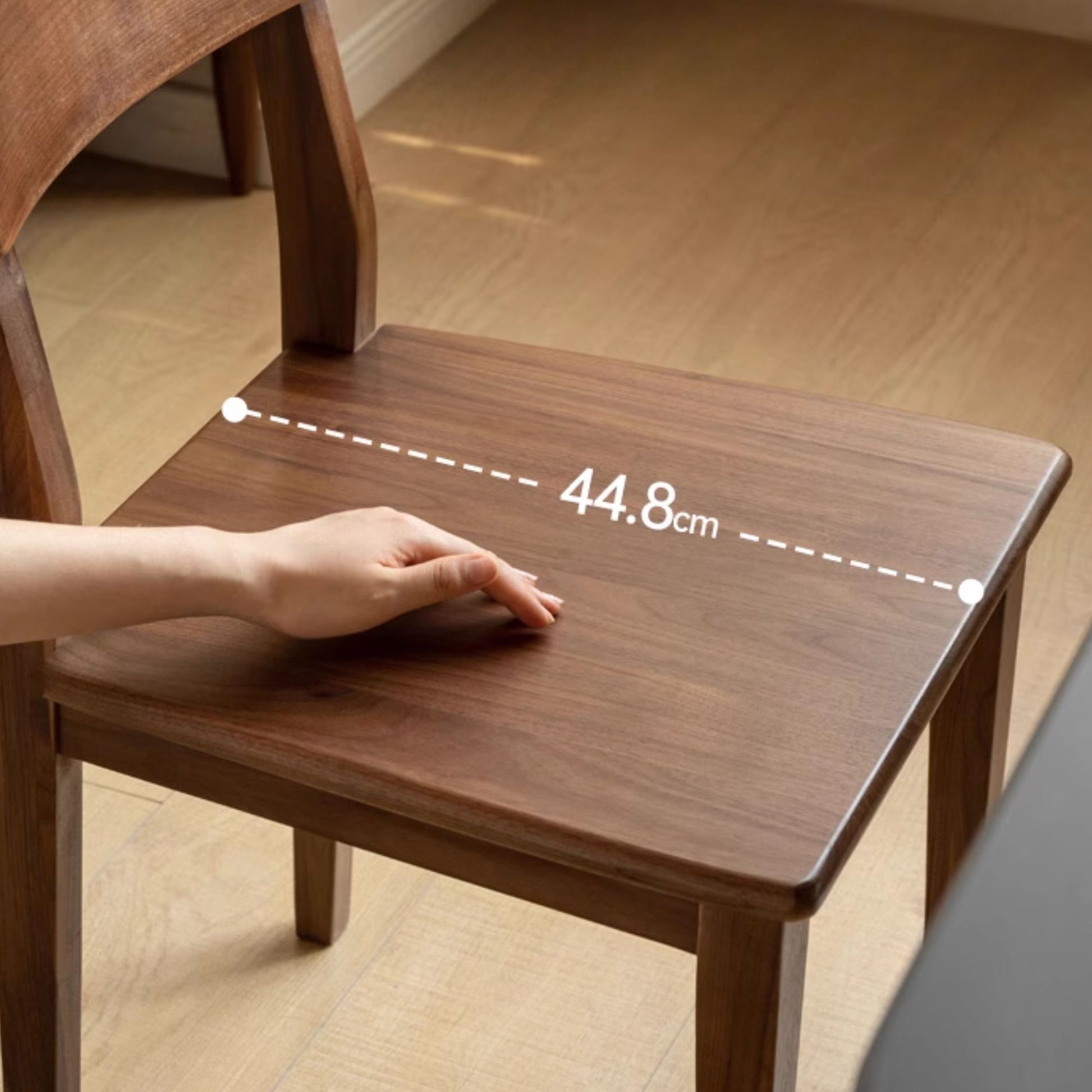 Wooden chair with a hand on it, showing measurement details.