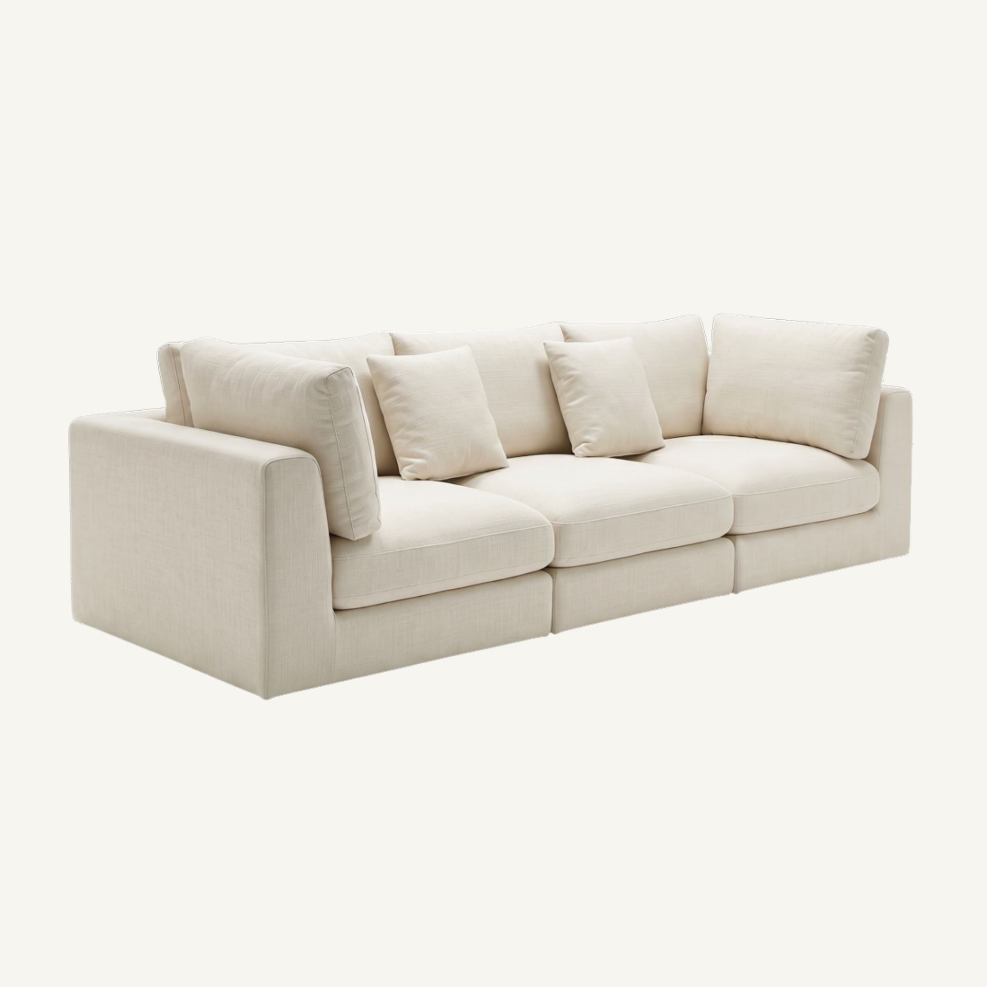 A modern three-seater sofa upholstered in a light cream or off-white textured fabric, featuring four matching square throw pillows, shown against a solid off-white background.
