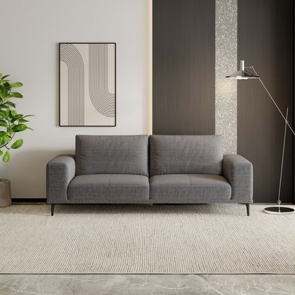 Gray sofa in a modern living room with a plant and wall art.