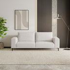 White sofa in a modern living room with a plant and abstract art on the wall.