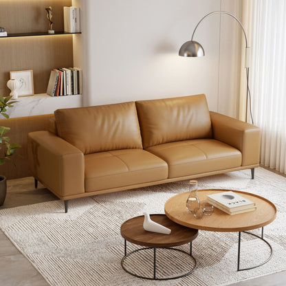 Brown leather sofa in a modern living room with coffee tables and decor.
