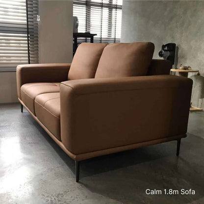 Brown sofa in a room with a concrete floor and window blinds.