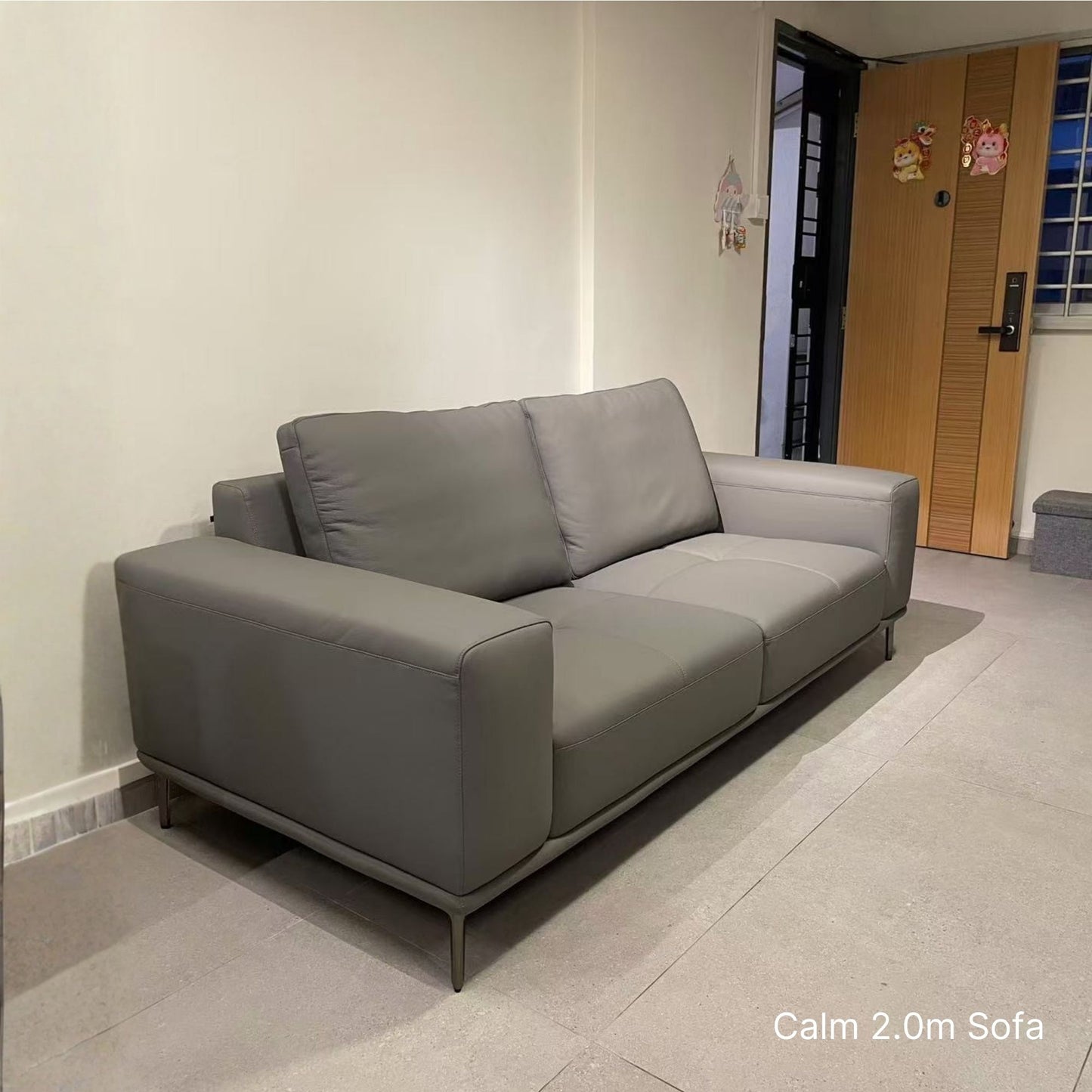 Gray sofa in a room with a door and wall decorations.
