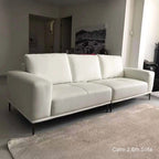 White sofa in a room with a gray rug and a painting on the wall.