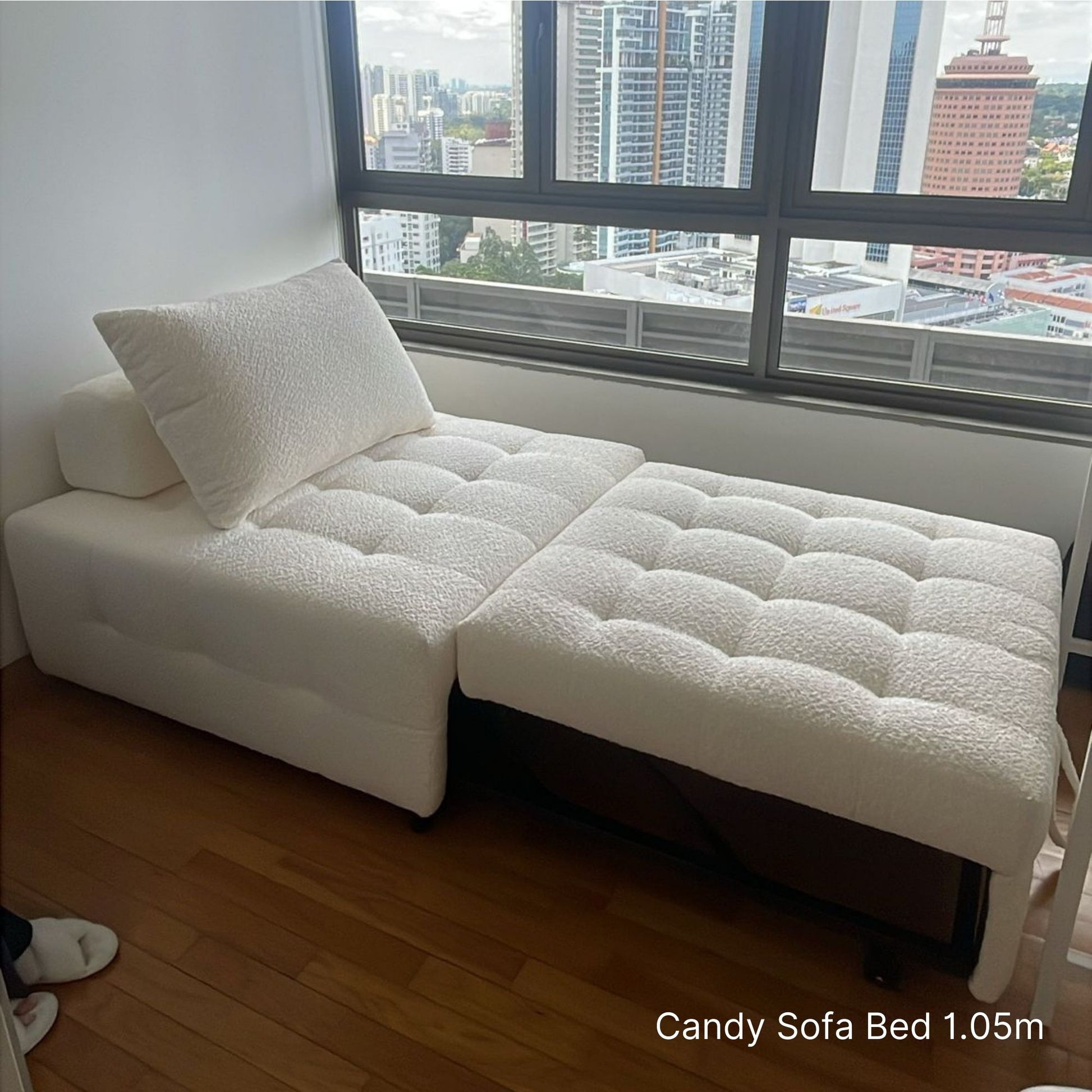 White sofa bed in a room with large windows showing a cityscape.