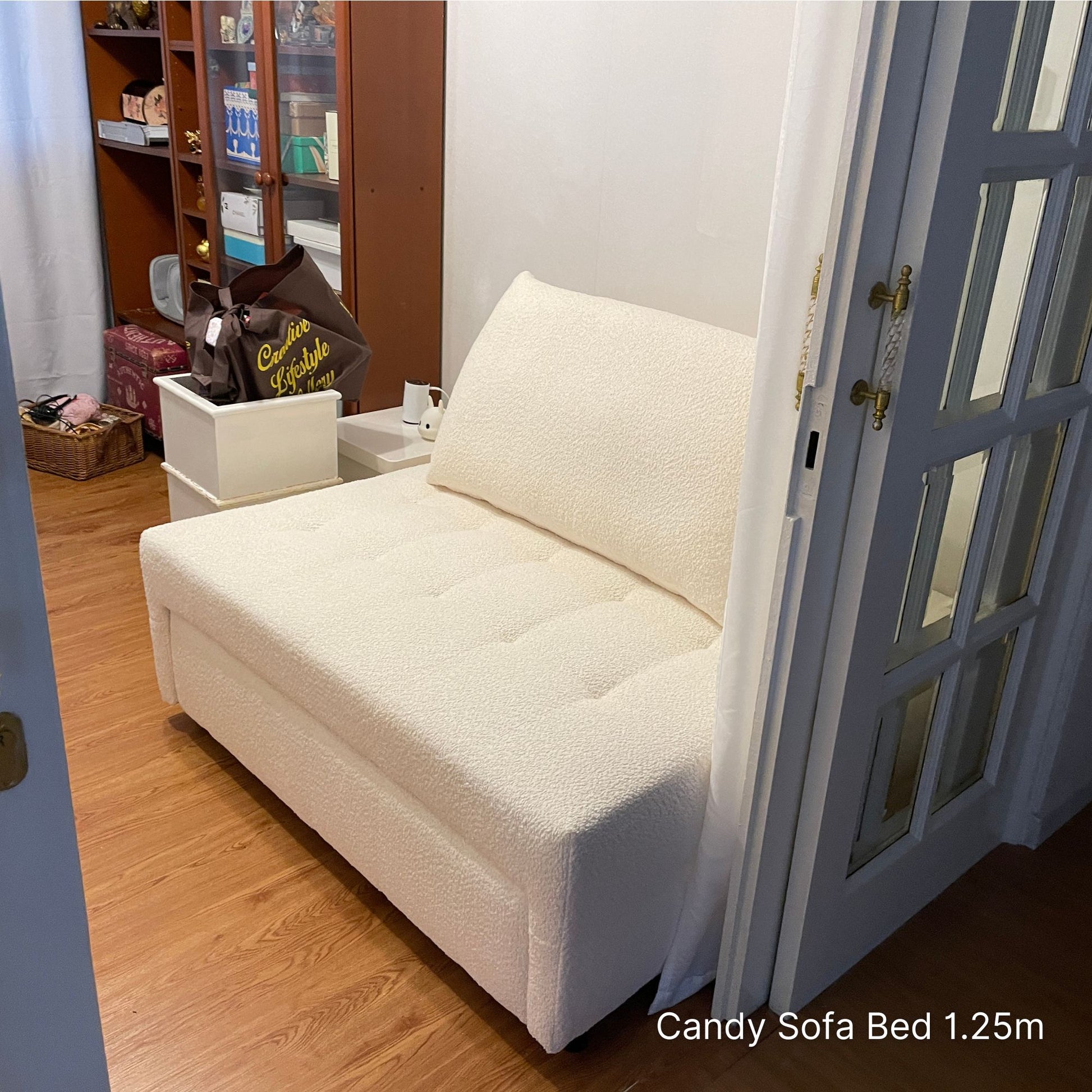 White sofa bed in a room with wooden floor and glass door