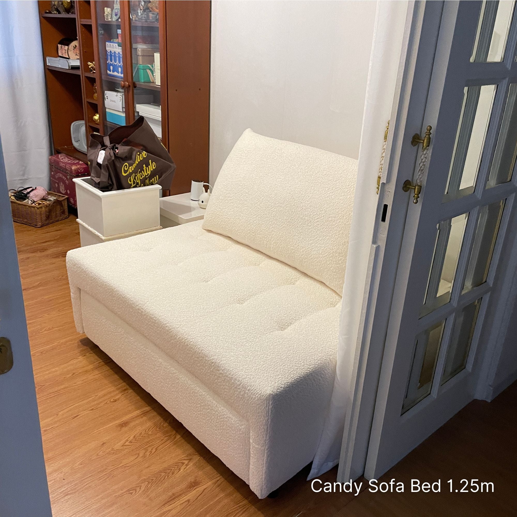 White sofa bed in a room with wooden floor and glass door