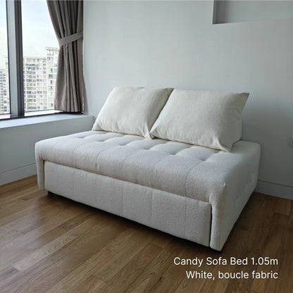 White sofa bed in a room with wooden flooring and a window.
