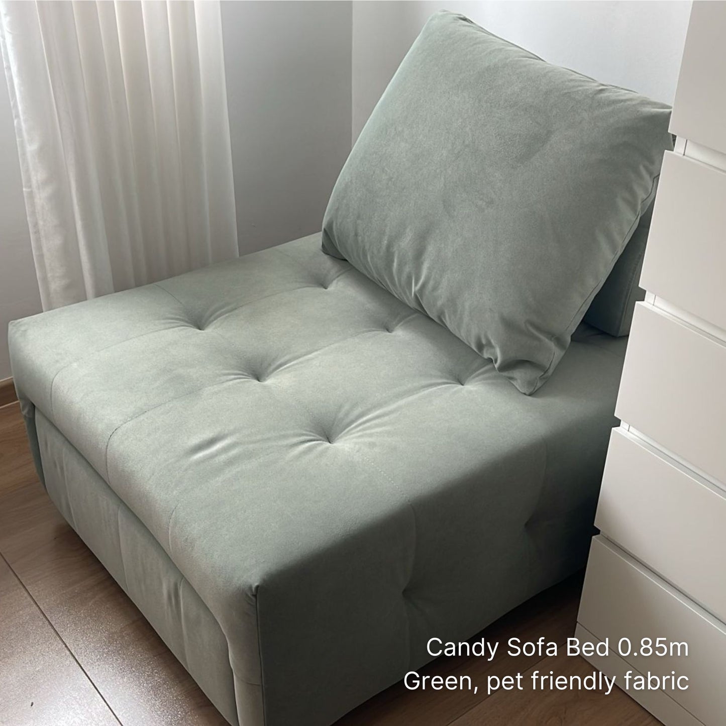 Green sofa bed with a pillow in a room setting