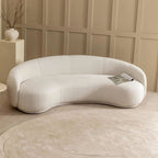 Modern white sofa against a beige paneled wall with a small table and decorative vase.