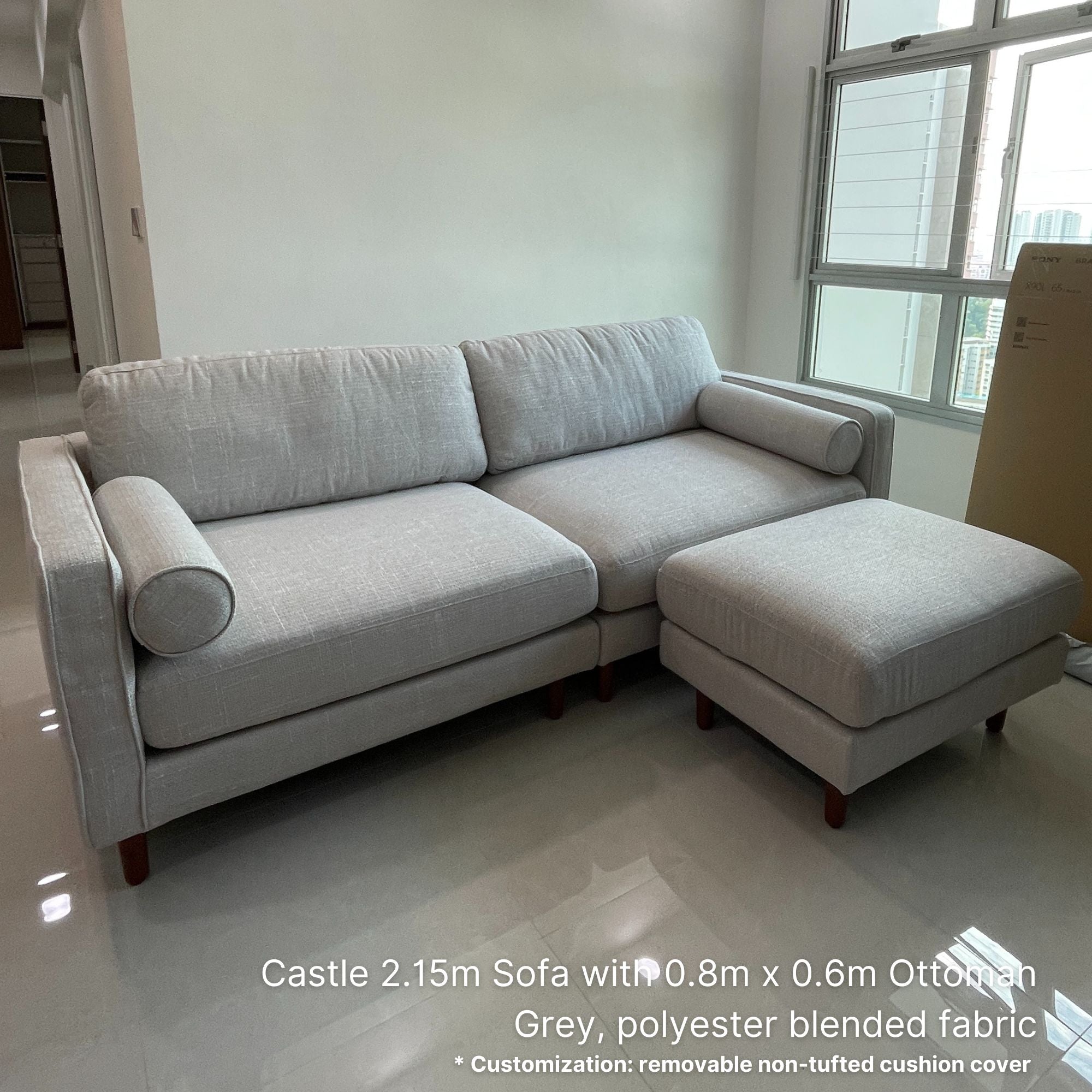 Gray sofa with ottoman in a room with large windows.