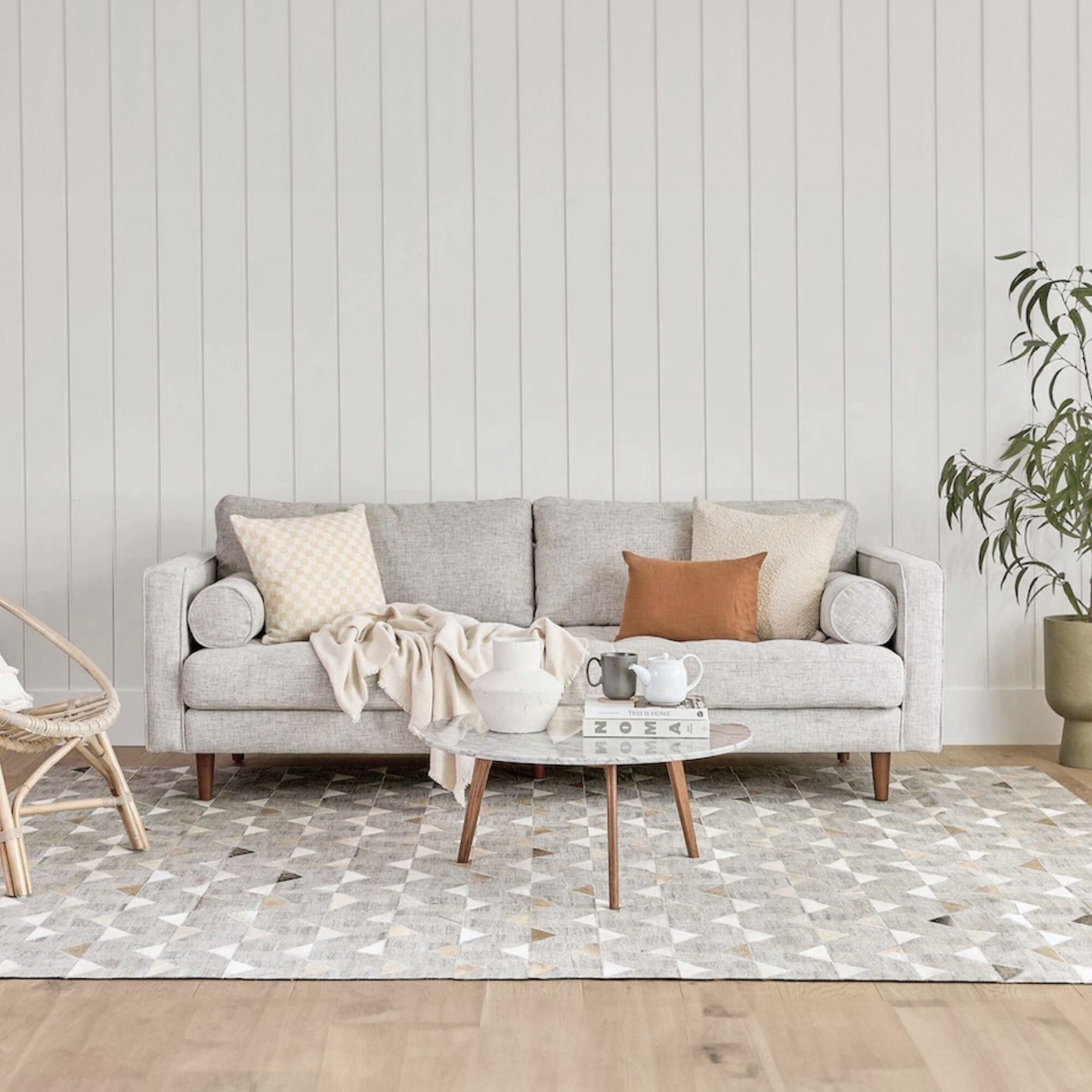 Living room with a gray sofa, coffee table, and decorative items against a light wood paneled wall.