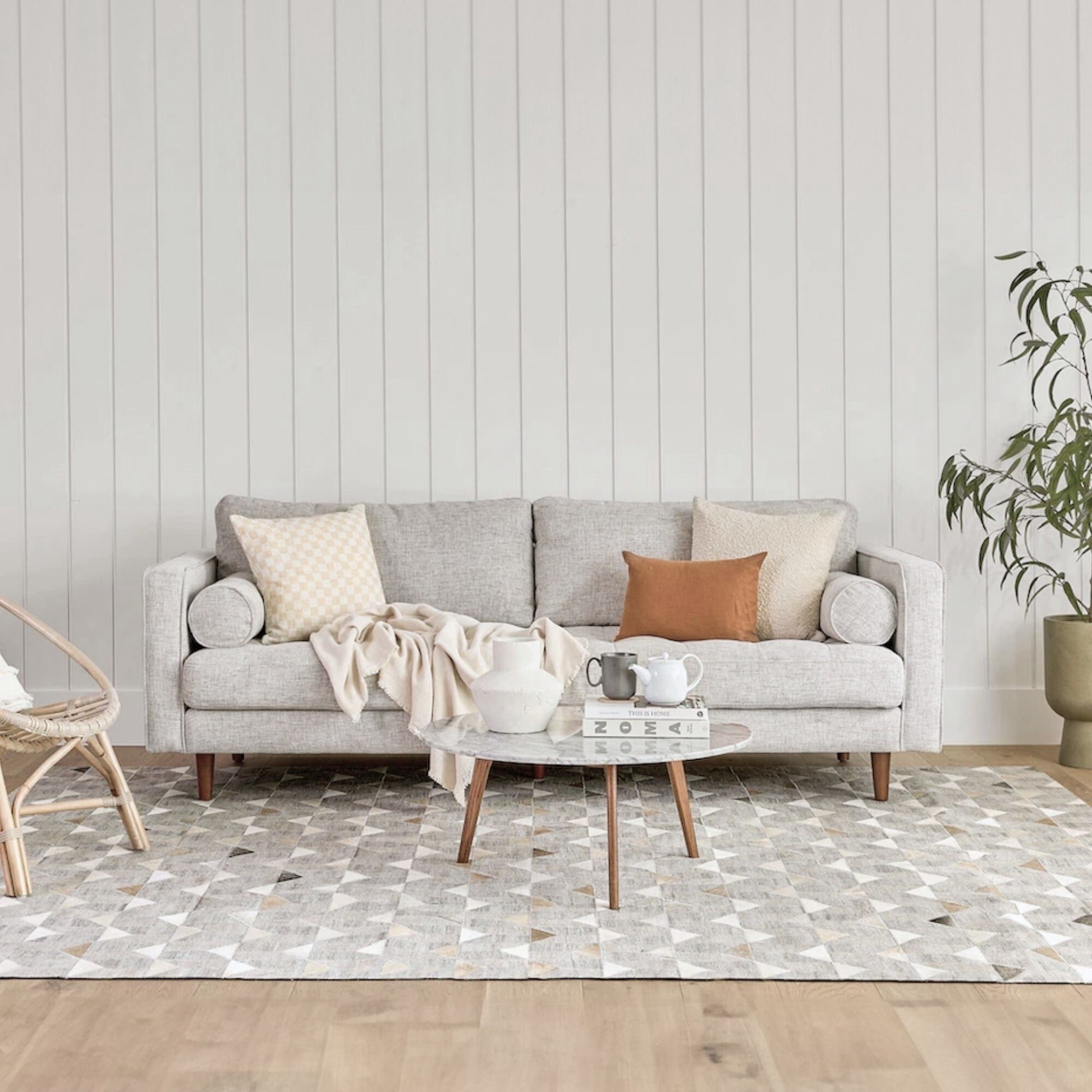 Living room with a gray sofa, coffee table, and decorative items against a light wood paneled wall.