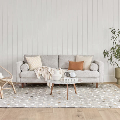 Living room with a gray sofa, coffee table, and decorative items against a light wood paneled wall.