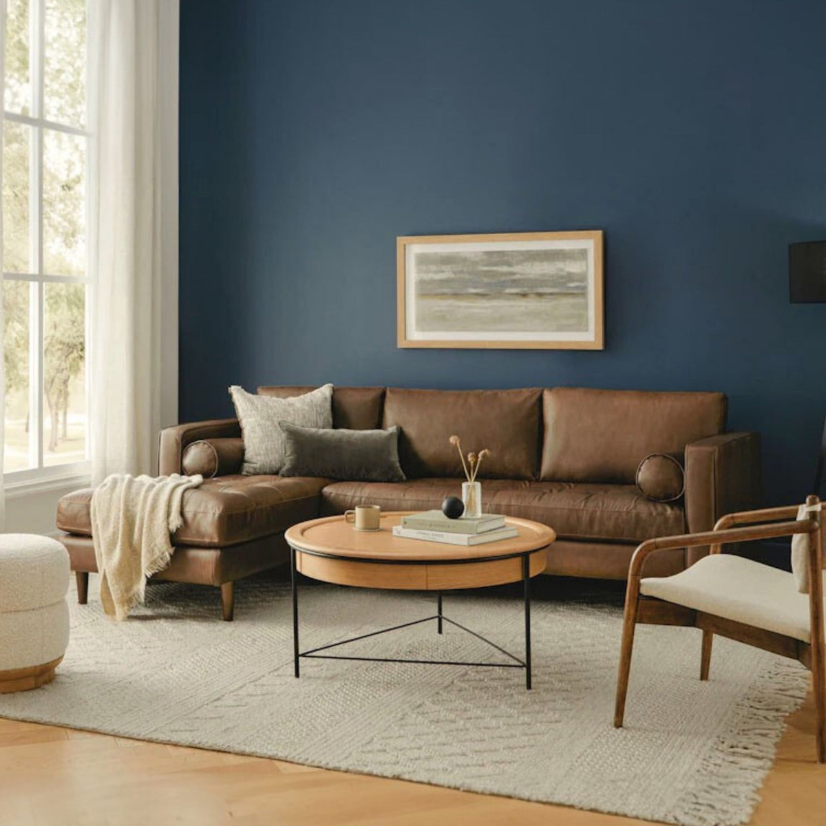 Living room with brown sectional sofa, round wooden coffee table, and blue wall.