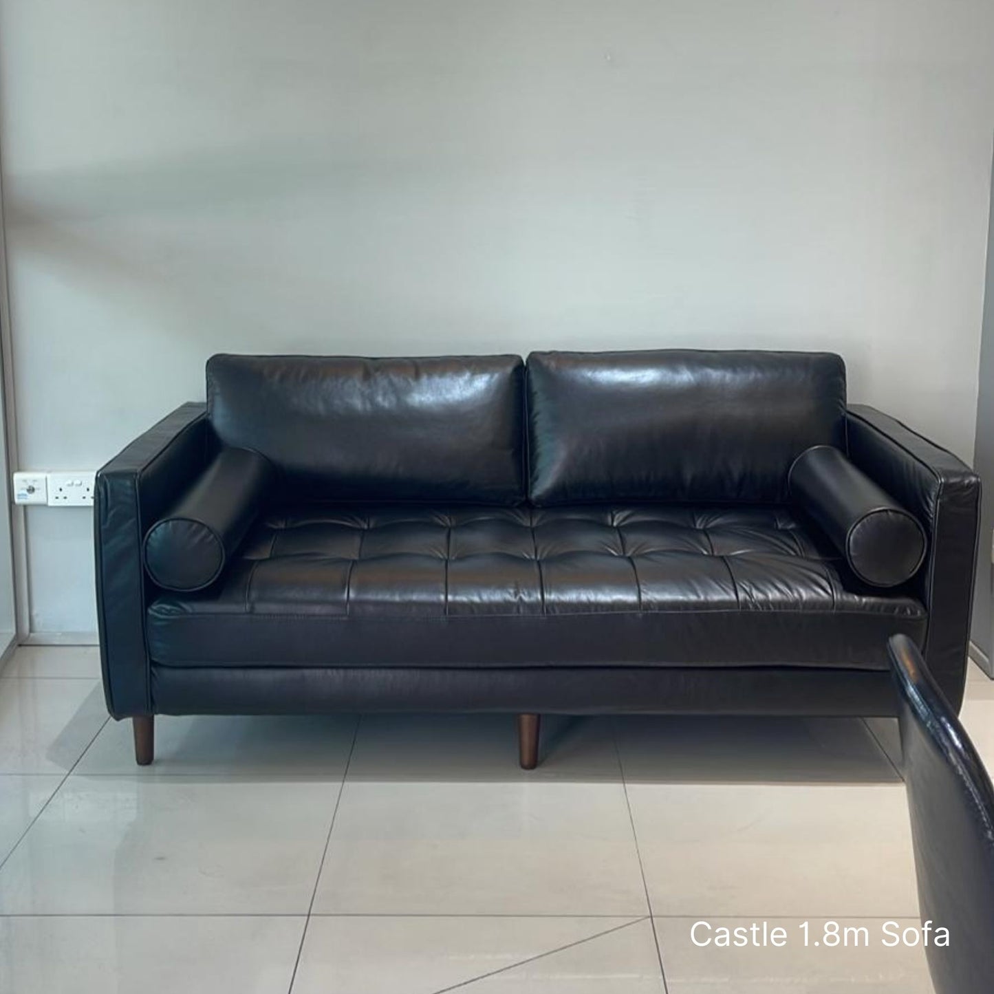 2 seater 180cm Castle black leather sofa in a room with tiled floor and white walls.