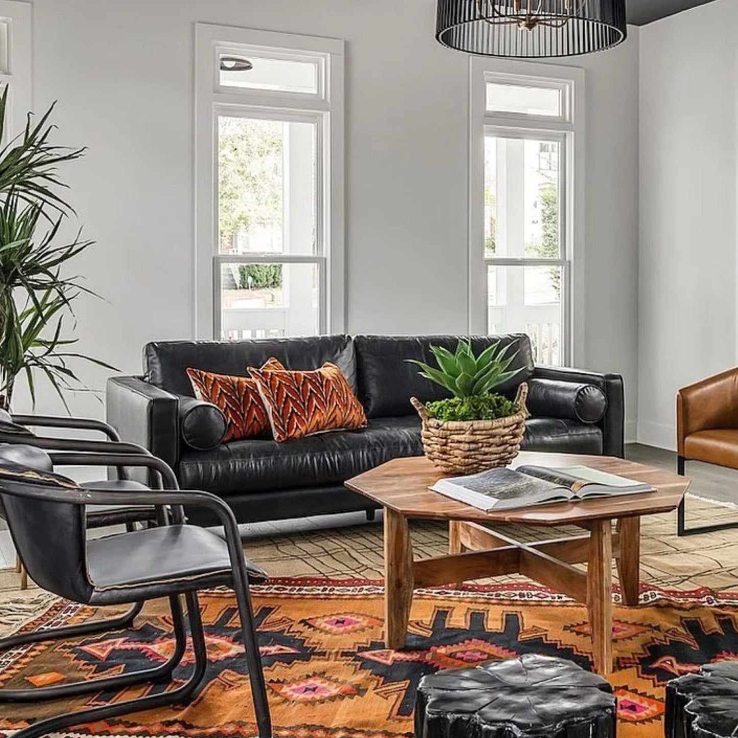 Modern living room with black leather sofa, wooden coffee table, and decorative elements.