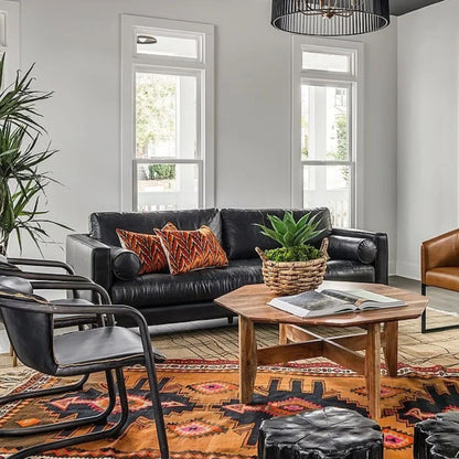Modern living room with black leather sofa, wooden coffee table, and decorative elements.