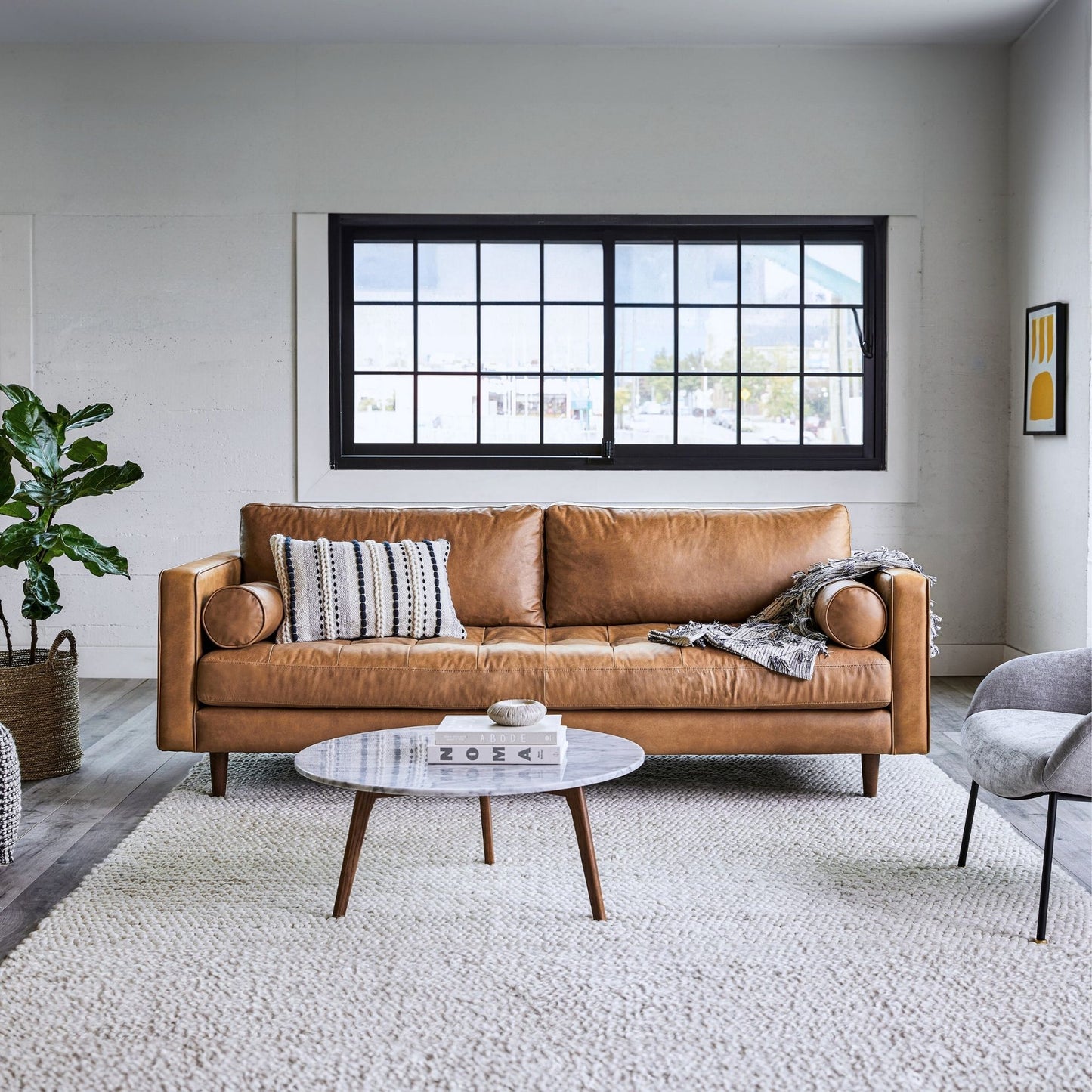 Modern living room with a brown leather sofa, coffee table, and decorative items.