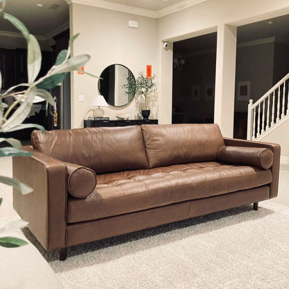 Brown leather sofa in a living room setting with decor elements.