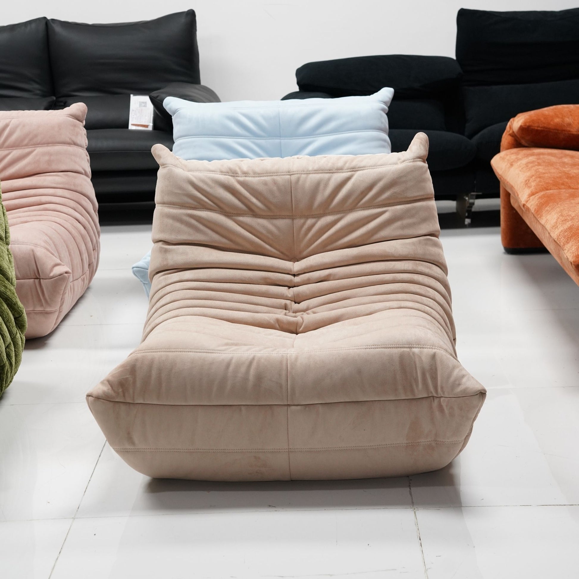 Beige cushioned lounge chair in a room with other colorful lounge chair and sofa