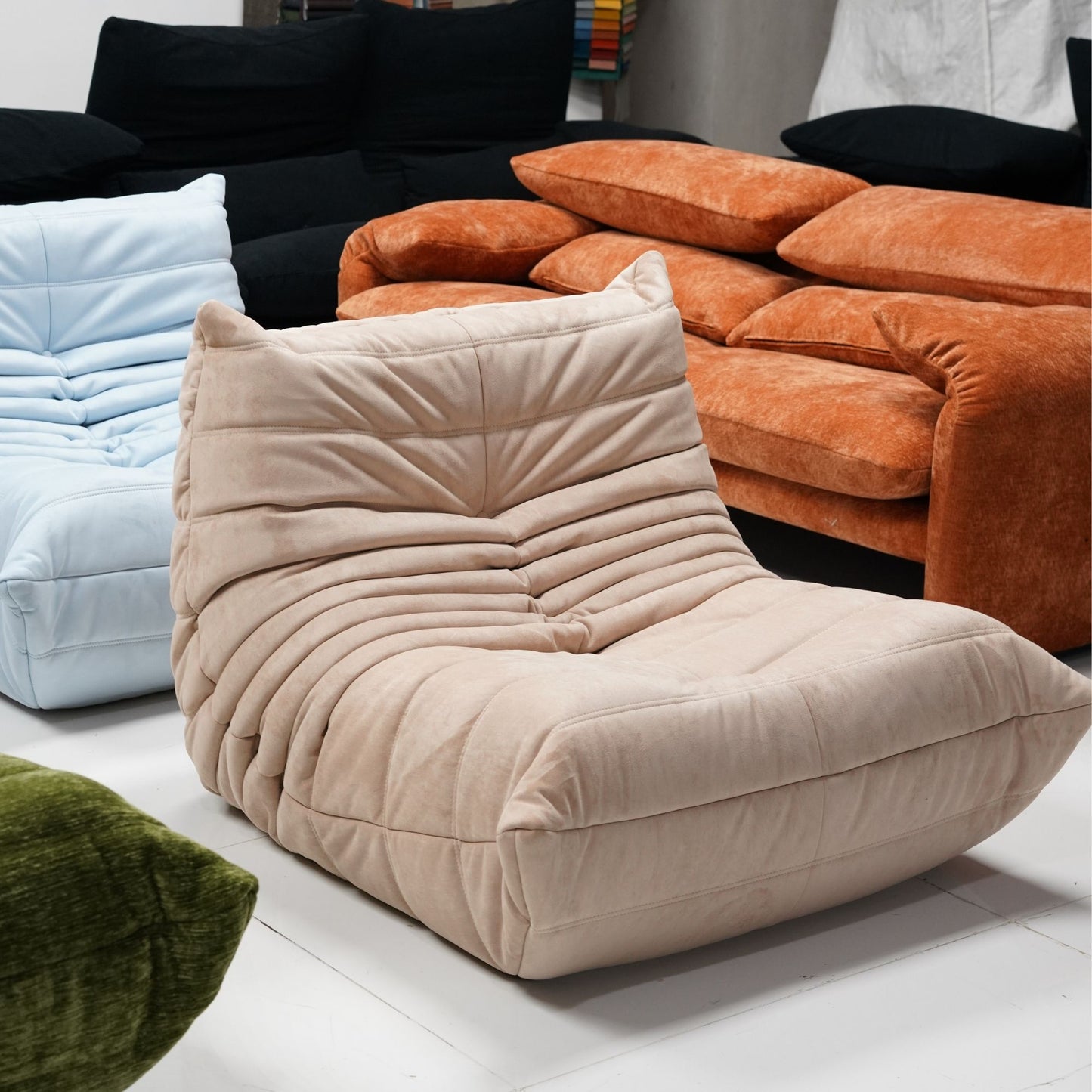 Beige lounge chair in a room with other colorful sofas and lounge chair