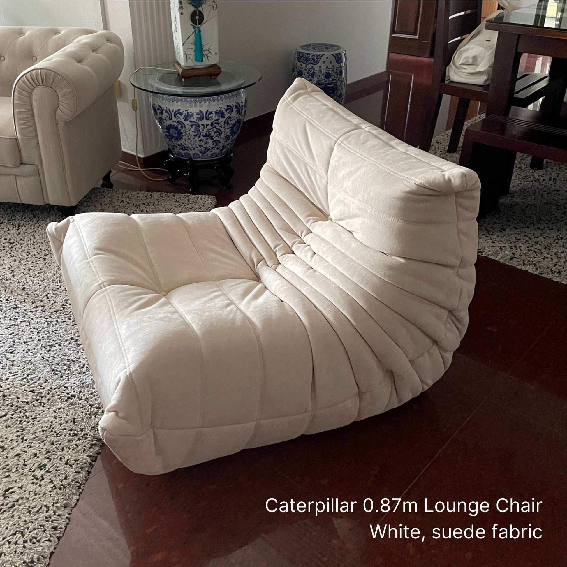 White suede lounge chair in a living room setting with furniture and decor.