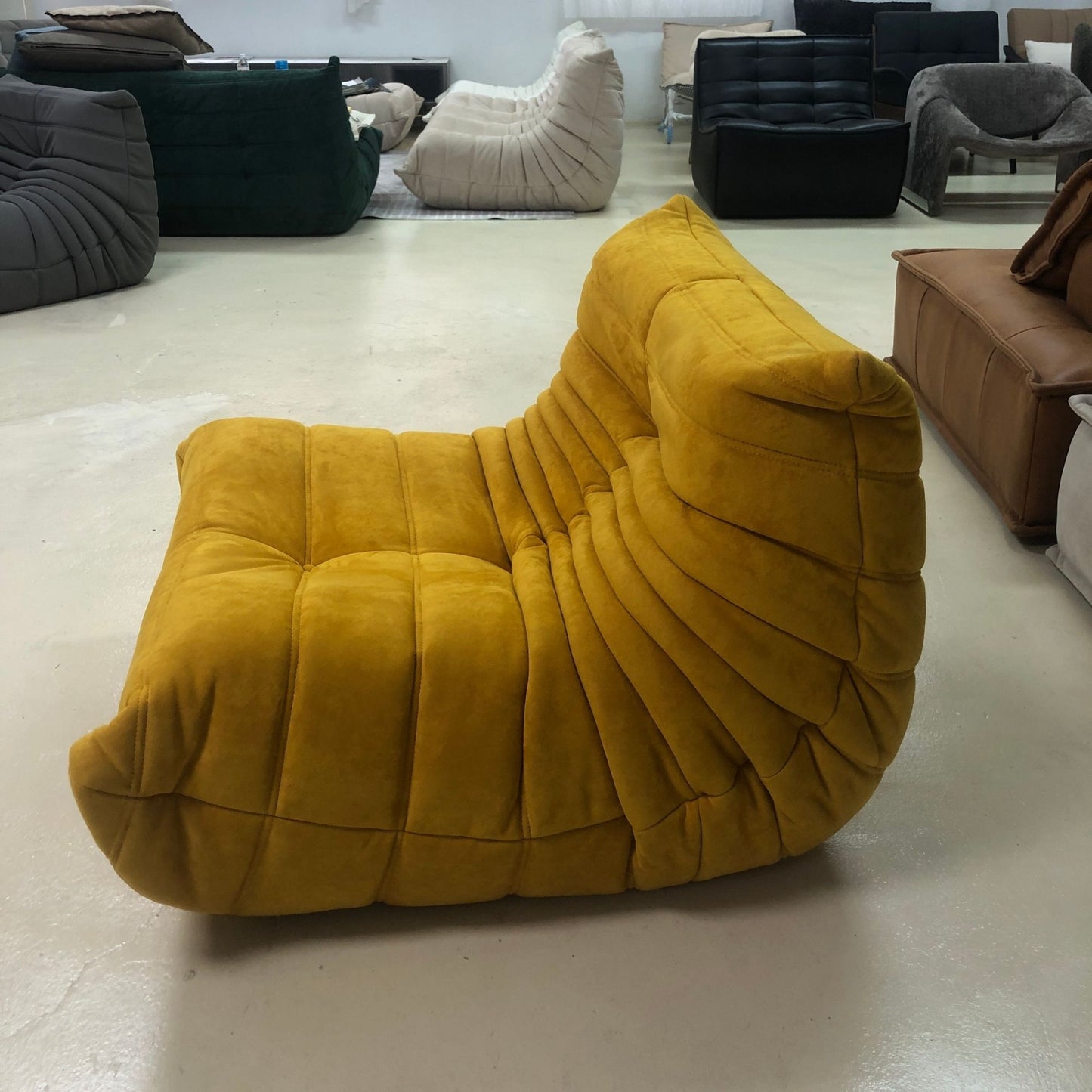 Yellow lounge chair in a showroom with other furniture.