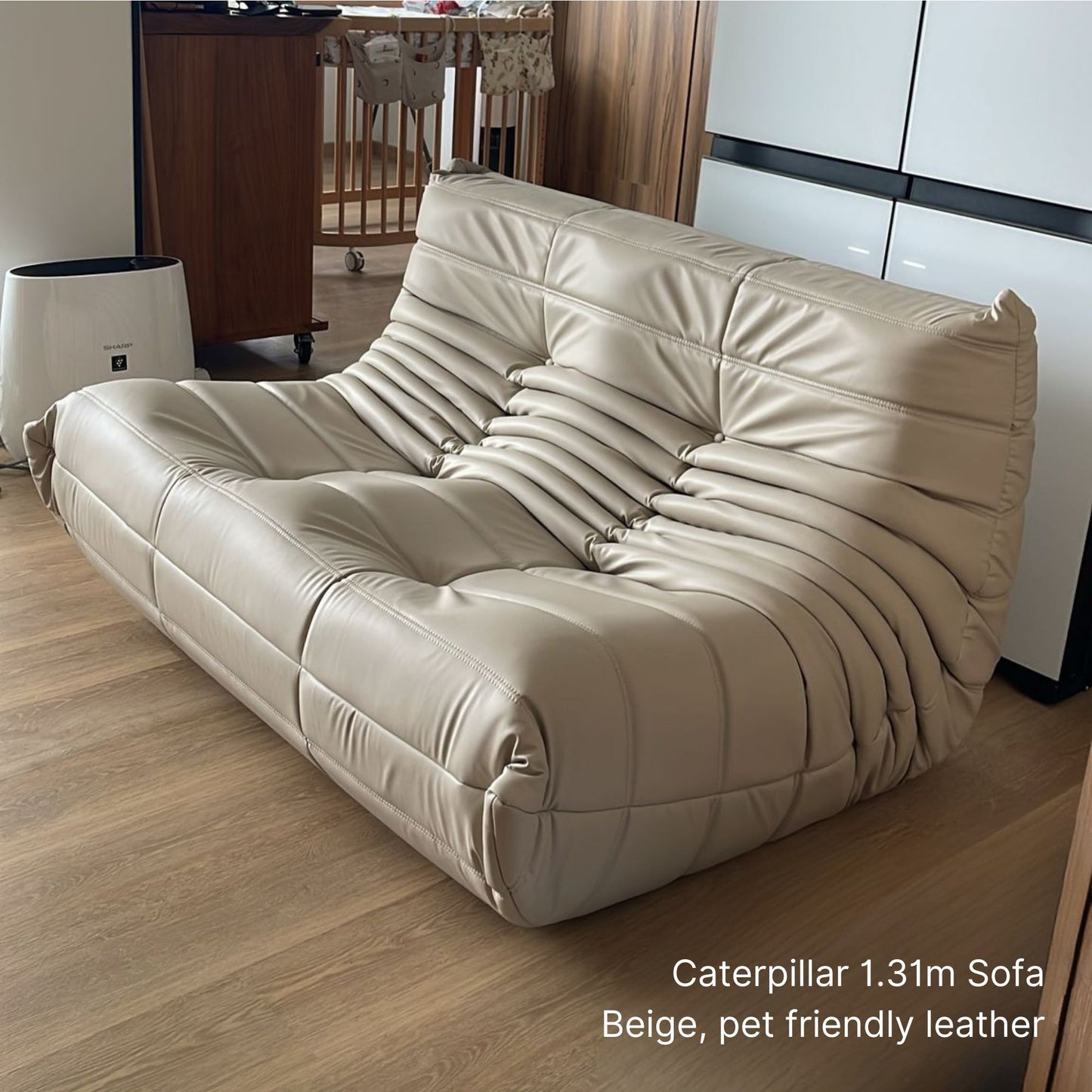 Beige 131cm 2 seater faux leather sofa in a room with wooden flooring and a white wall.