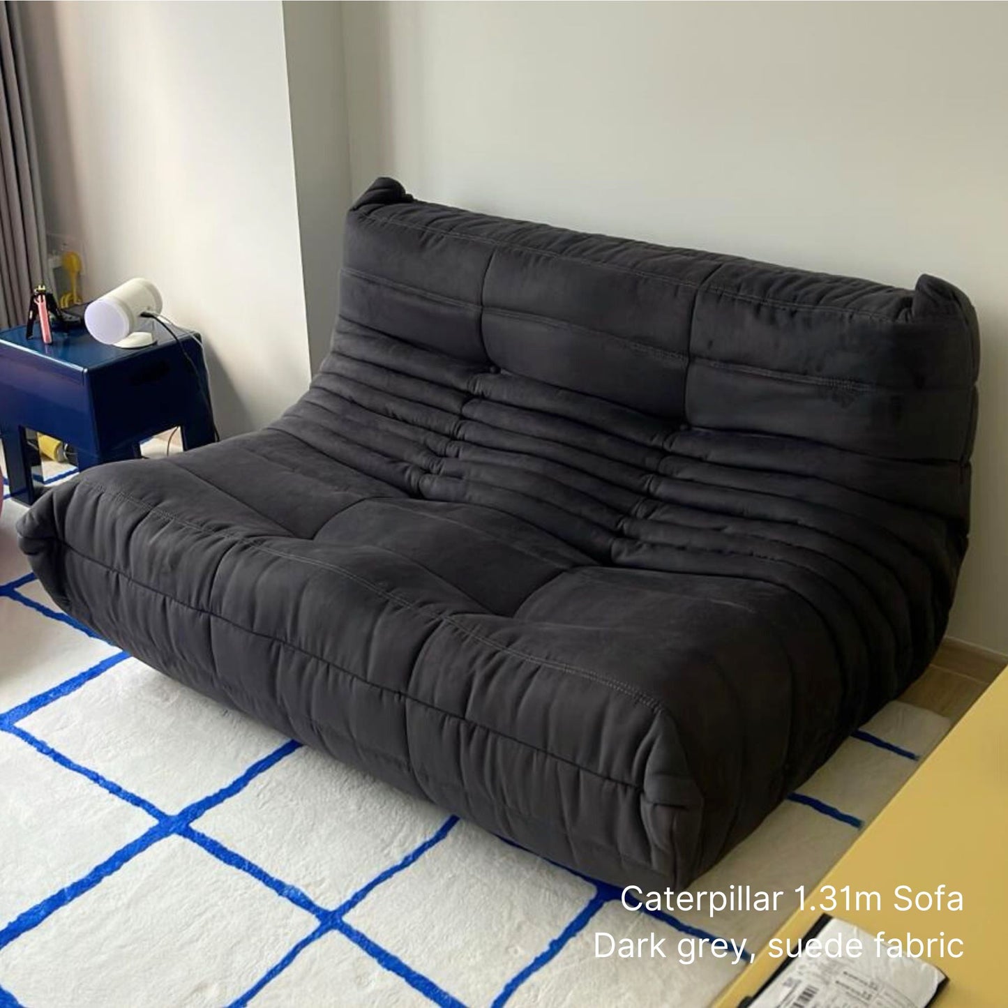 Dark grey 131cm 2 seater Caterpillar sofa on a white and blue checkered floor.