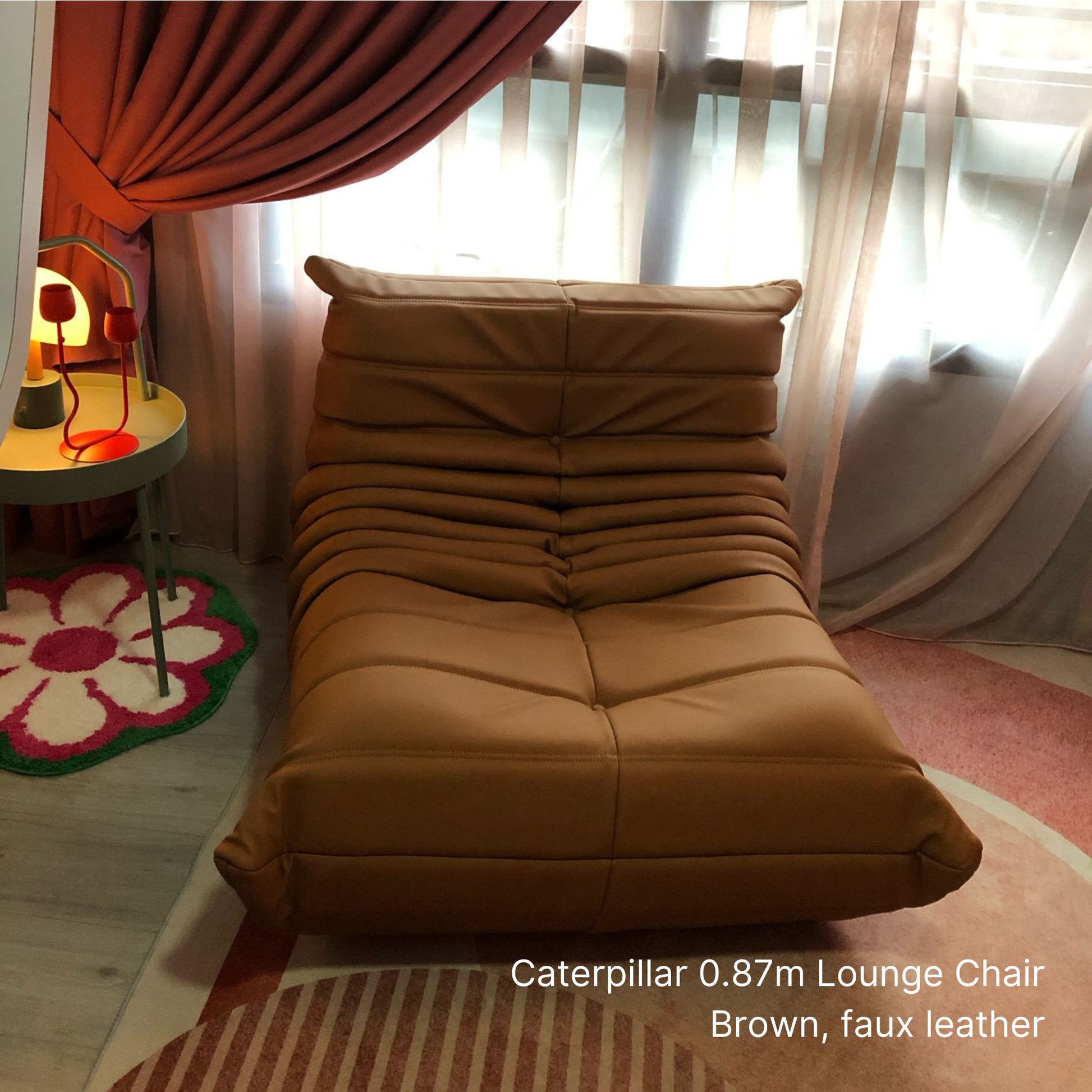 Brown faux leather Caterpillar lounge chair in a room with curtains and a small table.