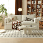 Celeste fabric sofa in living room setting with plant, coffee table, rug and bookshelf at the back