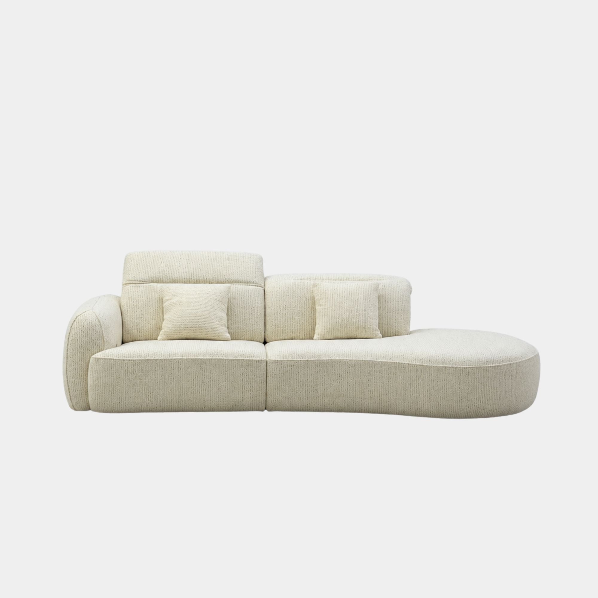 A modern curved modular sofa upholstered in a light beige textured fabric, featuring two matching square throw pillows, shown against a plain light gray background.