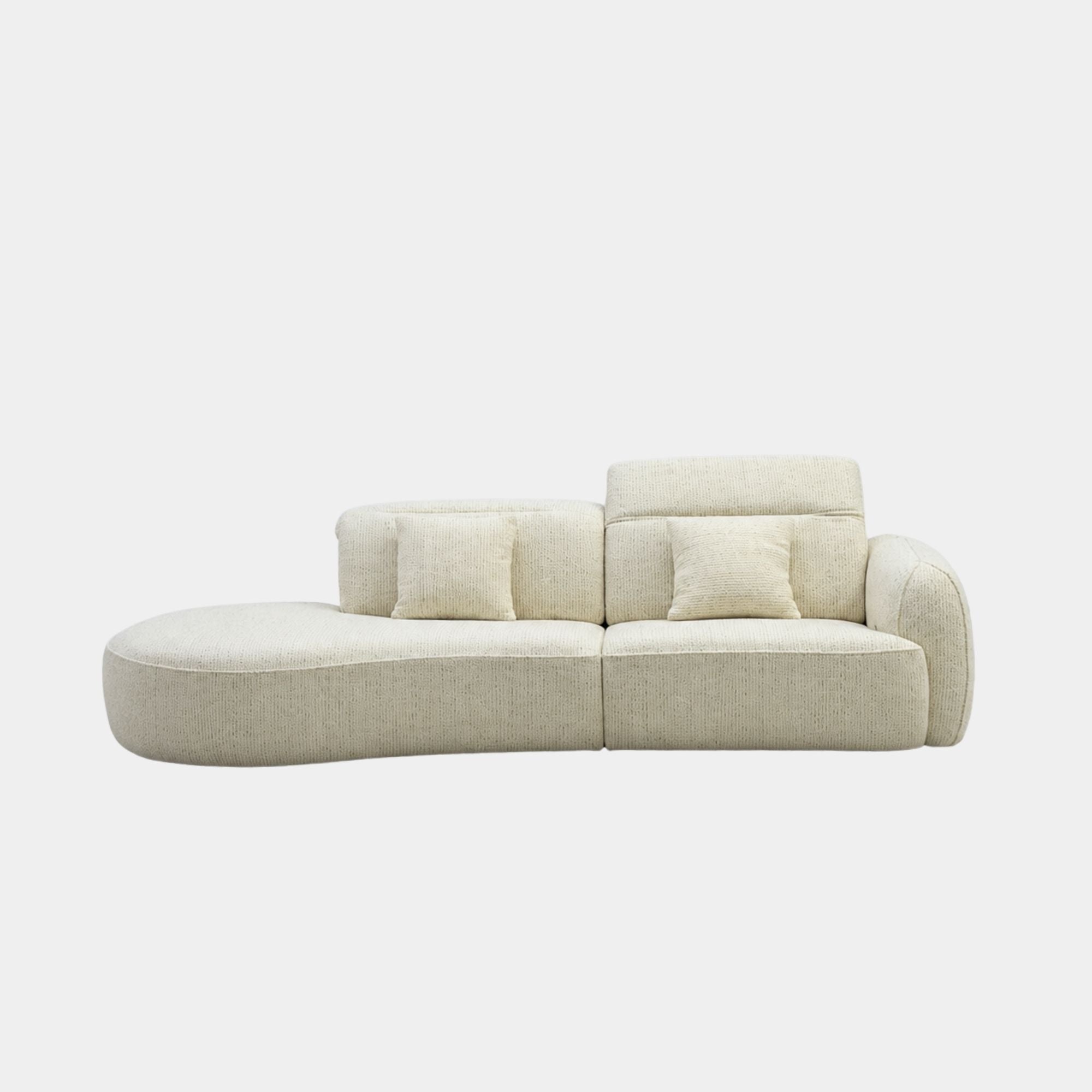 A modern curved modular sofa upholstered in a light beige textured fabric, featuring two matching throw pillows, shown against a plain light gray background.