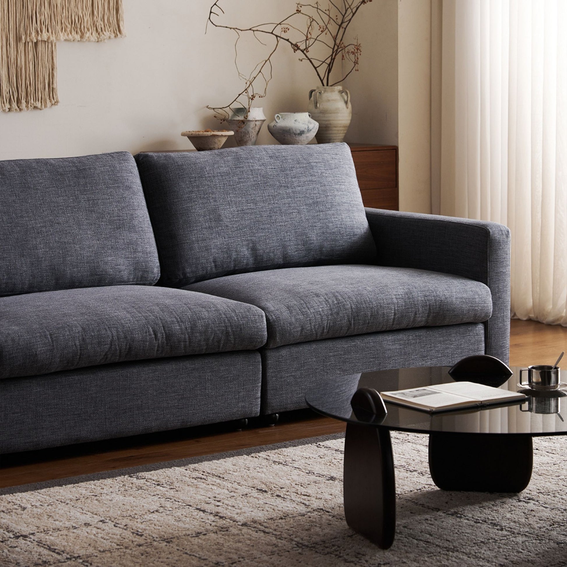 Gray sofa in a living room with a glass coffee table and decorative items.