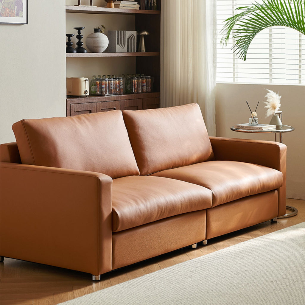 Brown leather sofa in a living room setting with a shelf and decor items.