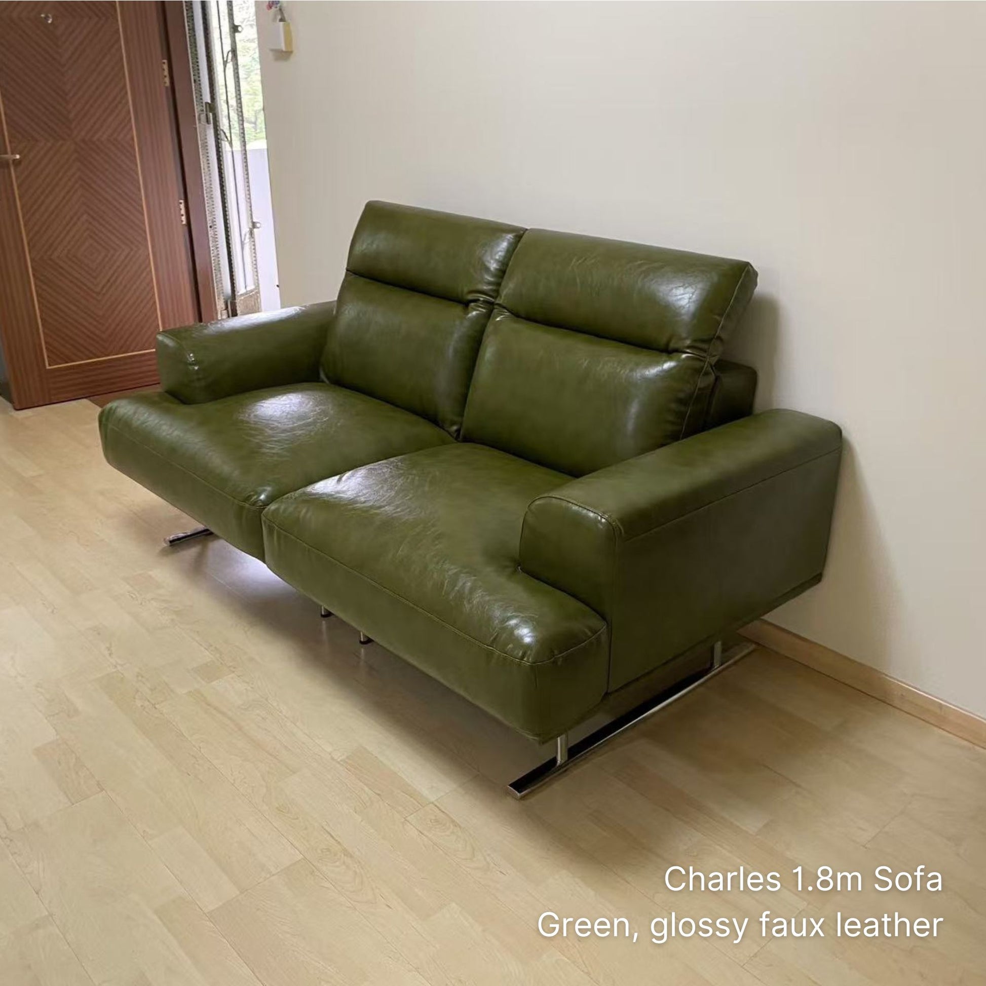 Green 2 seater 180cm Charles glossy faux leather sofa in a room with wooden floor and white walls.